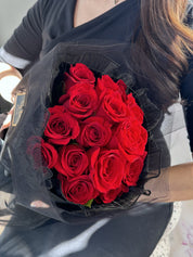 Person holding a red rose round bouquet with a full, rounded shape