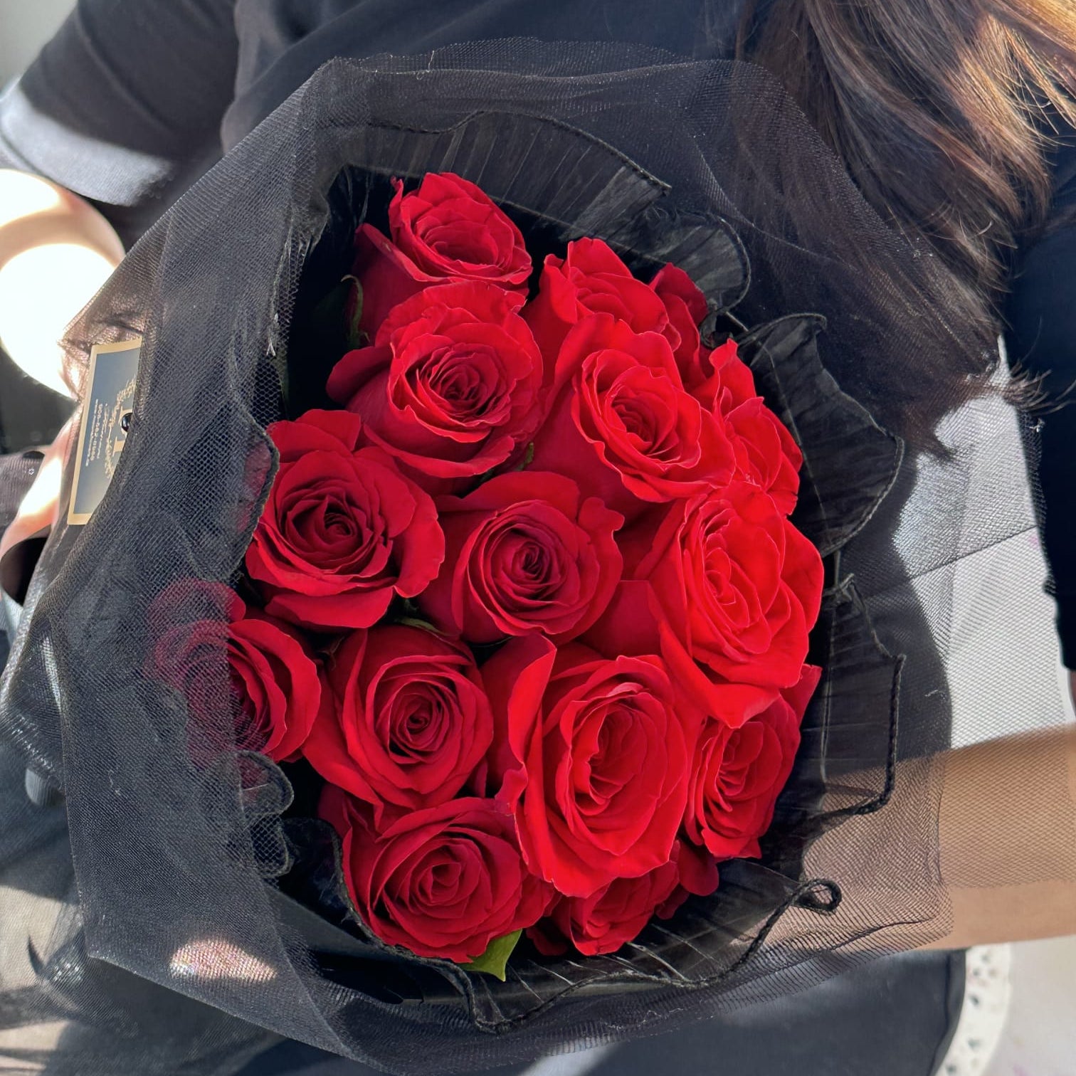 Person holding a red rose round bouquet with a full, rounded shape