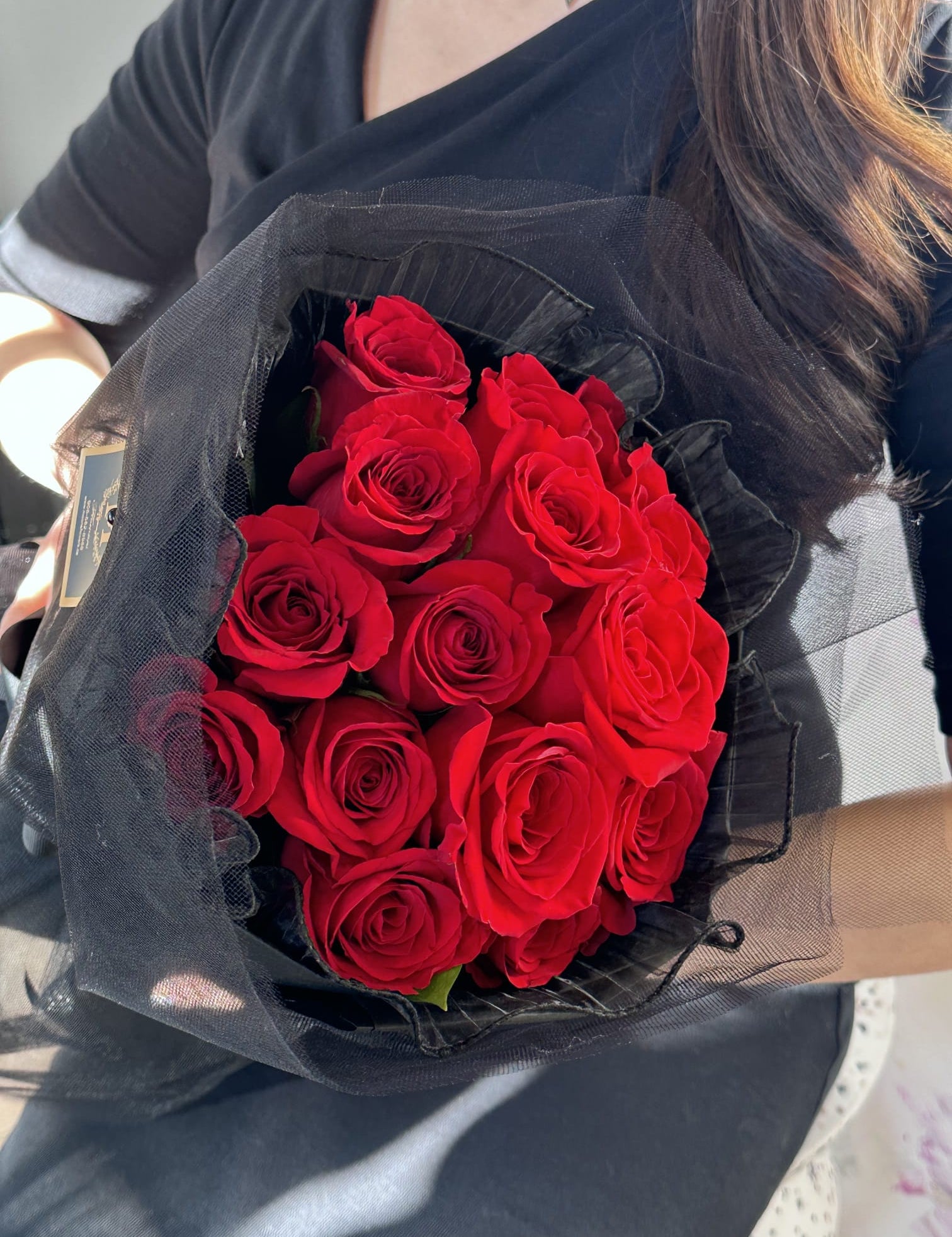 Person holding a red rose round bouquet with a full, rounded shape