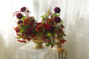 Autumn arrangement detail with red roses, seasonal berries, and russet leaves