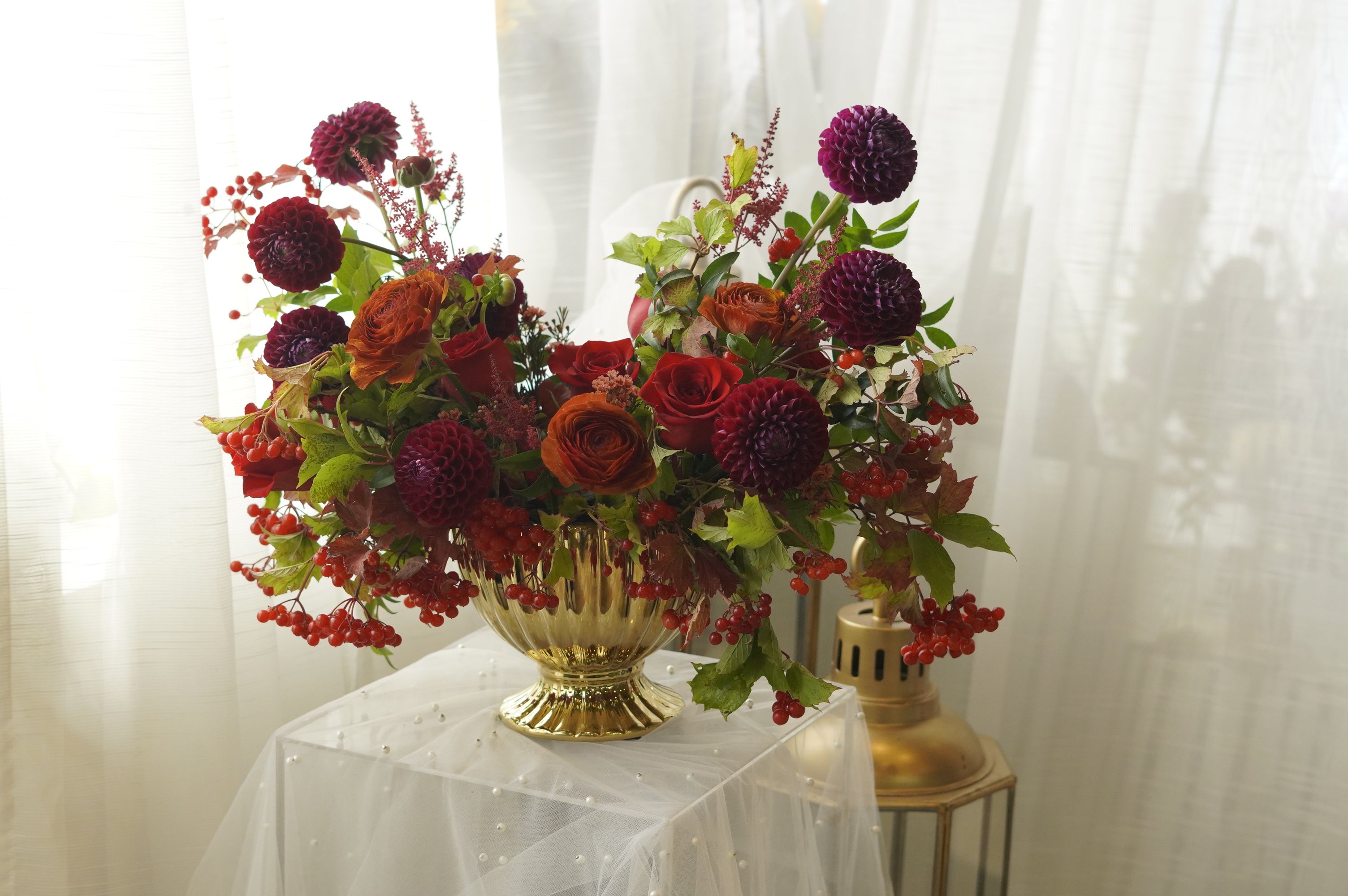 Autumn arrangement detail with red roses, seasonal berries, and russet leaves