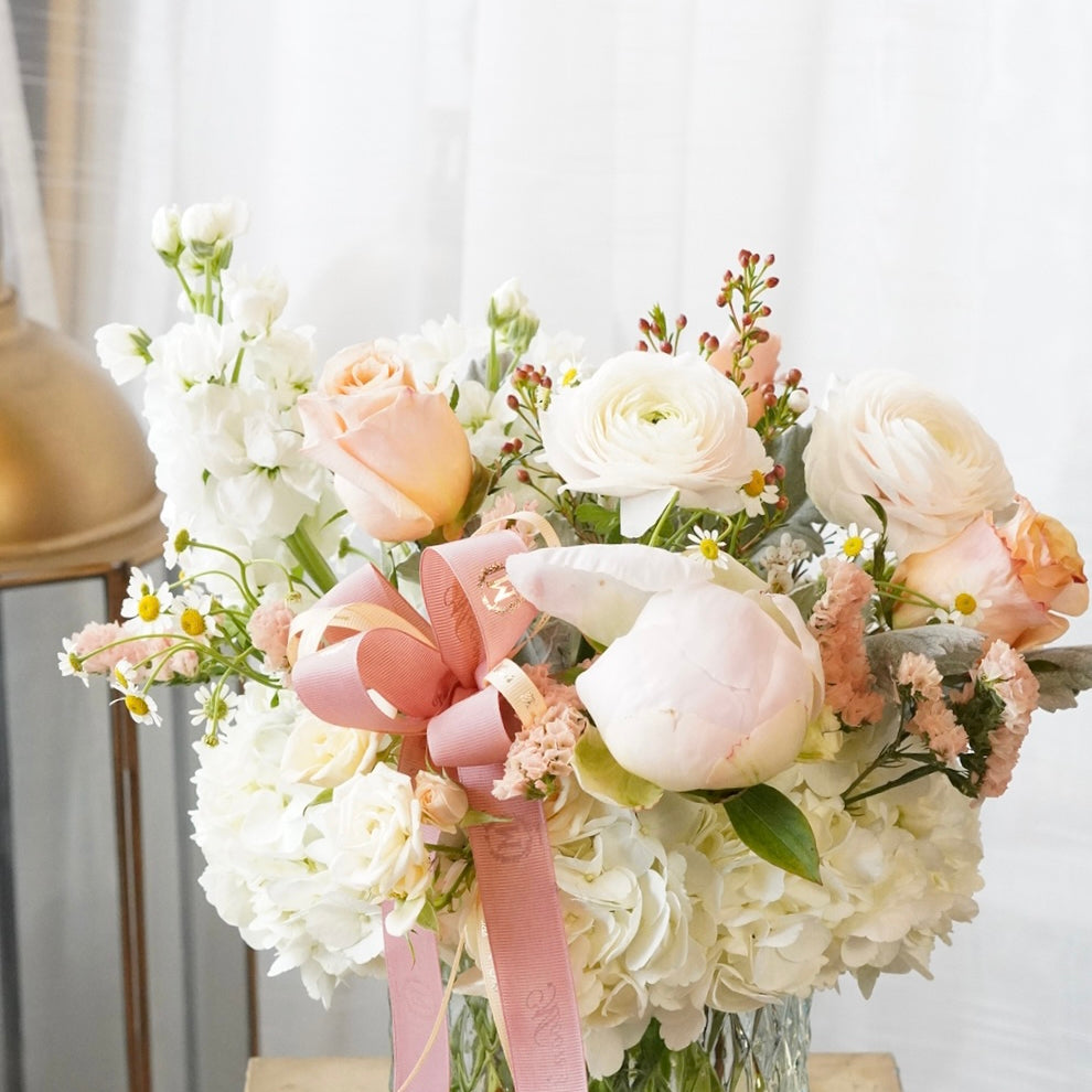 Bouquet of flowers with a pink ribbon in a clear vase on a wooden surface,For Mother's day. Toronto,Oakville delivery