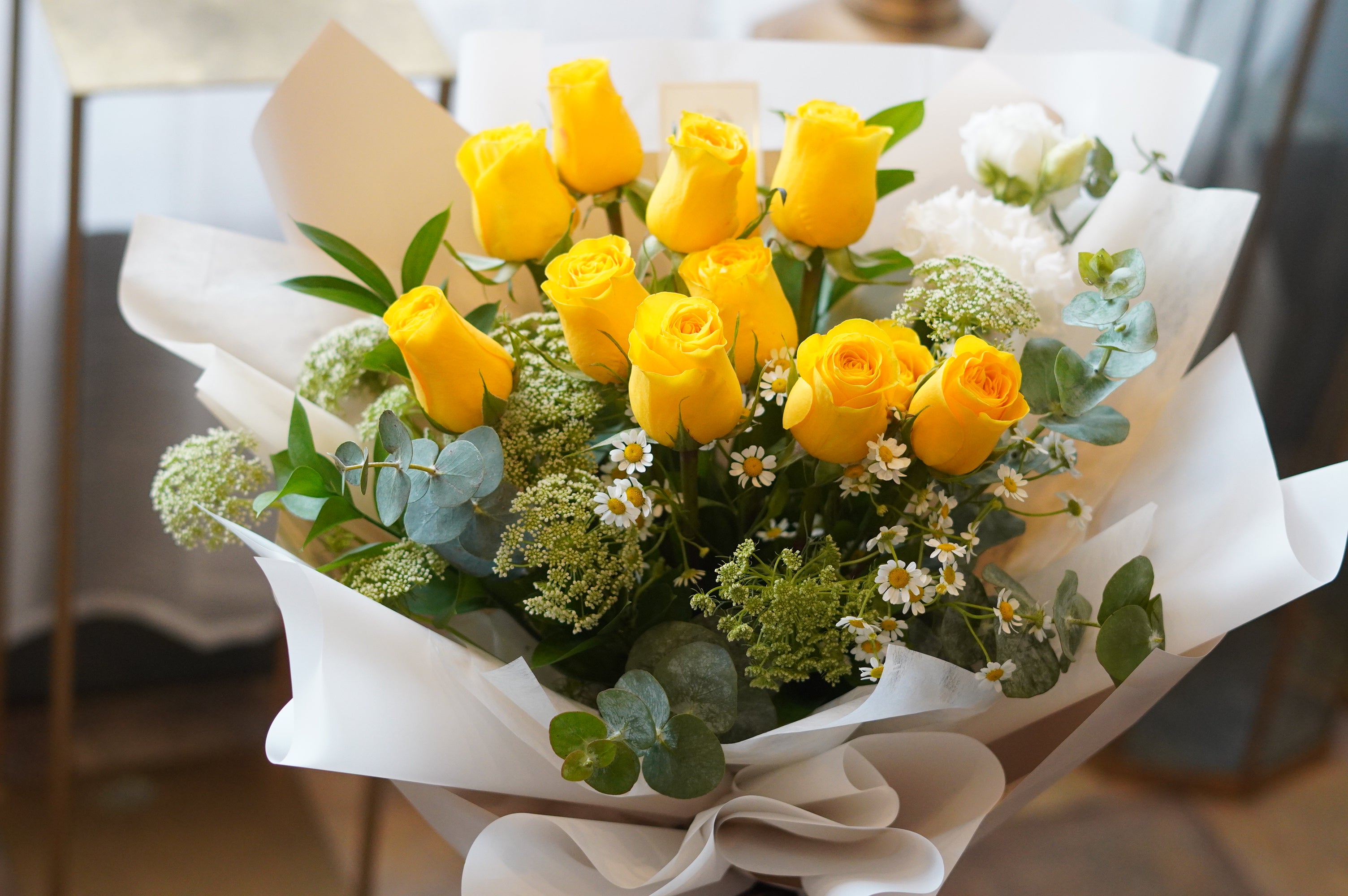 Fresh yellow rose bouquet in white Korean wrapping displayed on white stand – Moon's Flowers Toronto florist
