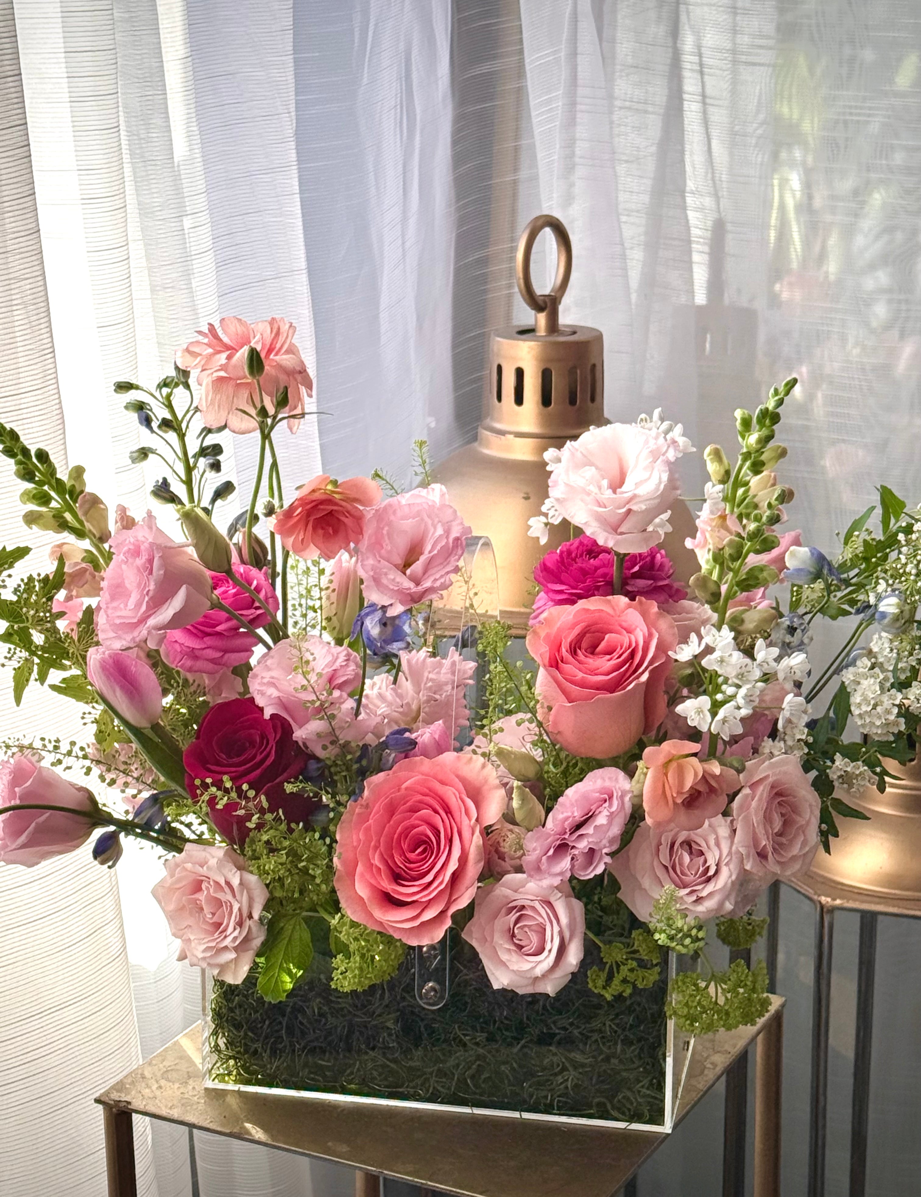 Floral arrangement in a decorative box with pink and white flowers on a table.