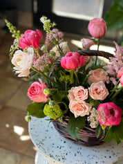 A close-up side view of the Mother's Day flower basket featuring pink peonies, garden roses, and delicate white blossoms in a dark wicker basket. Beautifully arranged seasonal flowers by Moon's Flowers Toronto