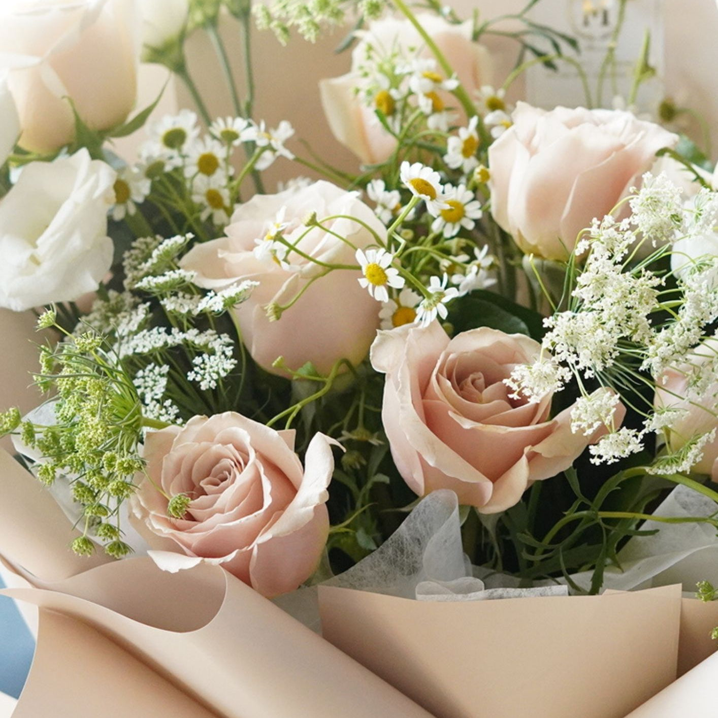 A dreamy and natural hand-tied bouquet with champagne-toned roses and fresh chamomile flower, offering a sophisticated spring garden look.