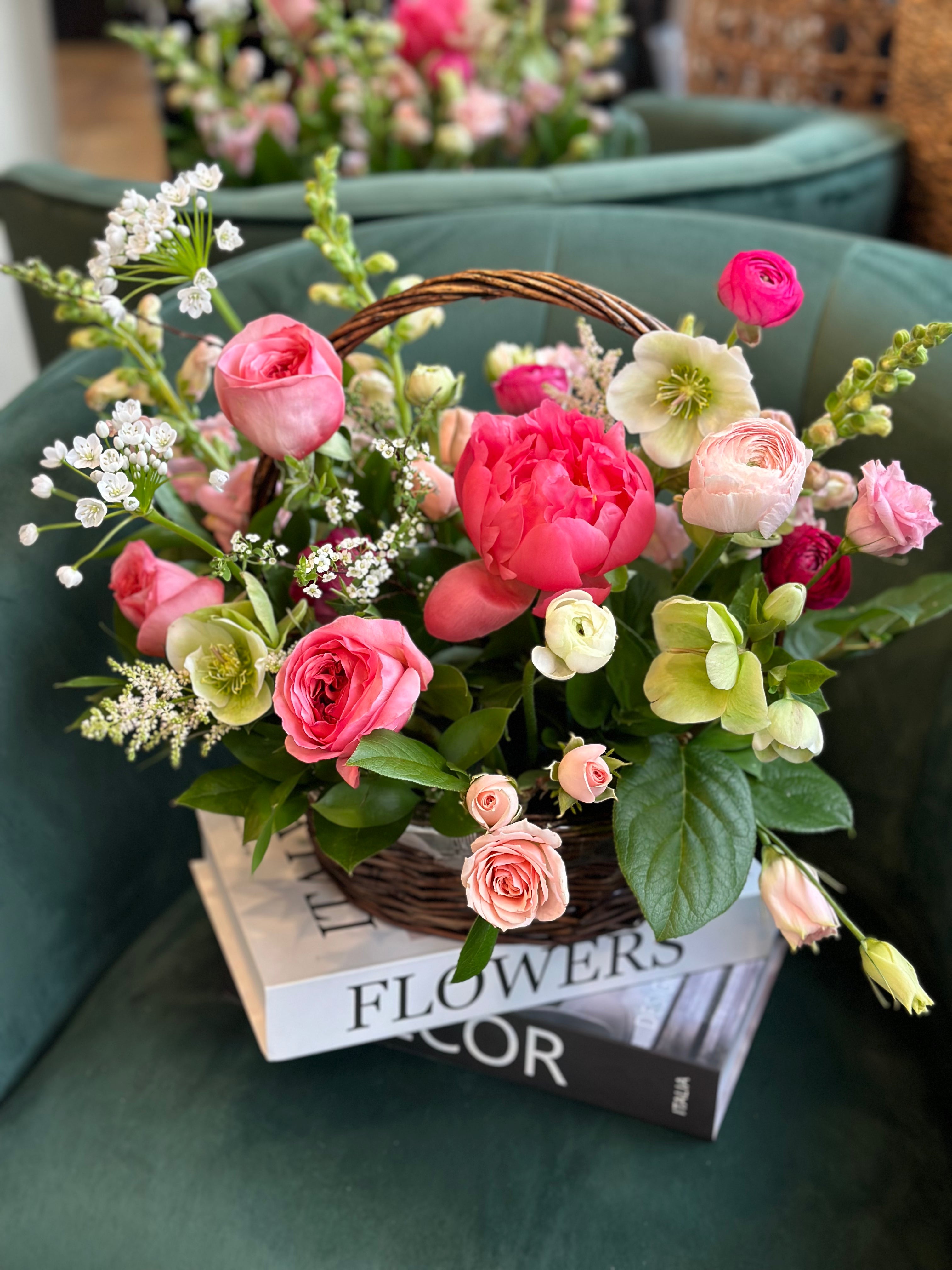 A lush Mother's Day flower basket featuring vibrant pink peonies, roses, and white hellebores in a rustic wicker basket. This elegant spring arrangement by Moon's Flowers Toronto is perfect for same-day delivery