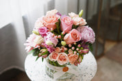 A lush pink rose and carnation centerpiece styled on a gold side table. Sophisticated 'Pretty Pink' Mother's Day floral gift professionally arranged by a top-rated Toronto florist