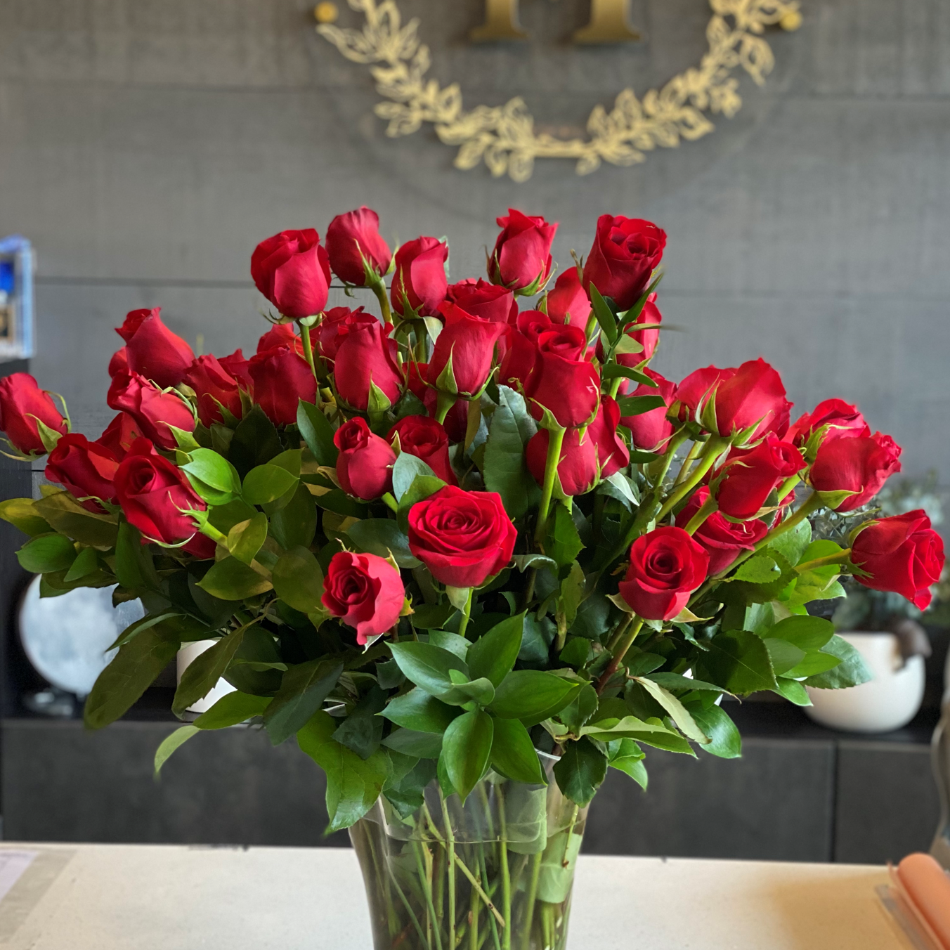 • A luxurious Mother's Day arrangement of premium red roses professionally arranged in a tall clear glass vase.
• Set against a modern background with Moon's Flowers signature gold logo, this elegant rose display is perfect for home delivery in Toronto.