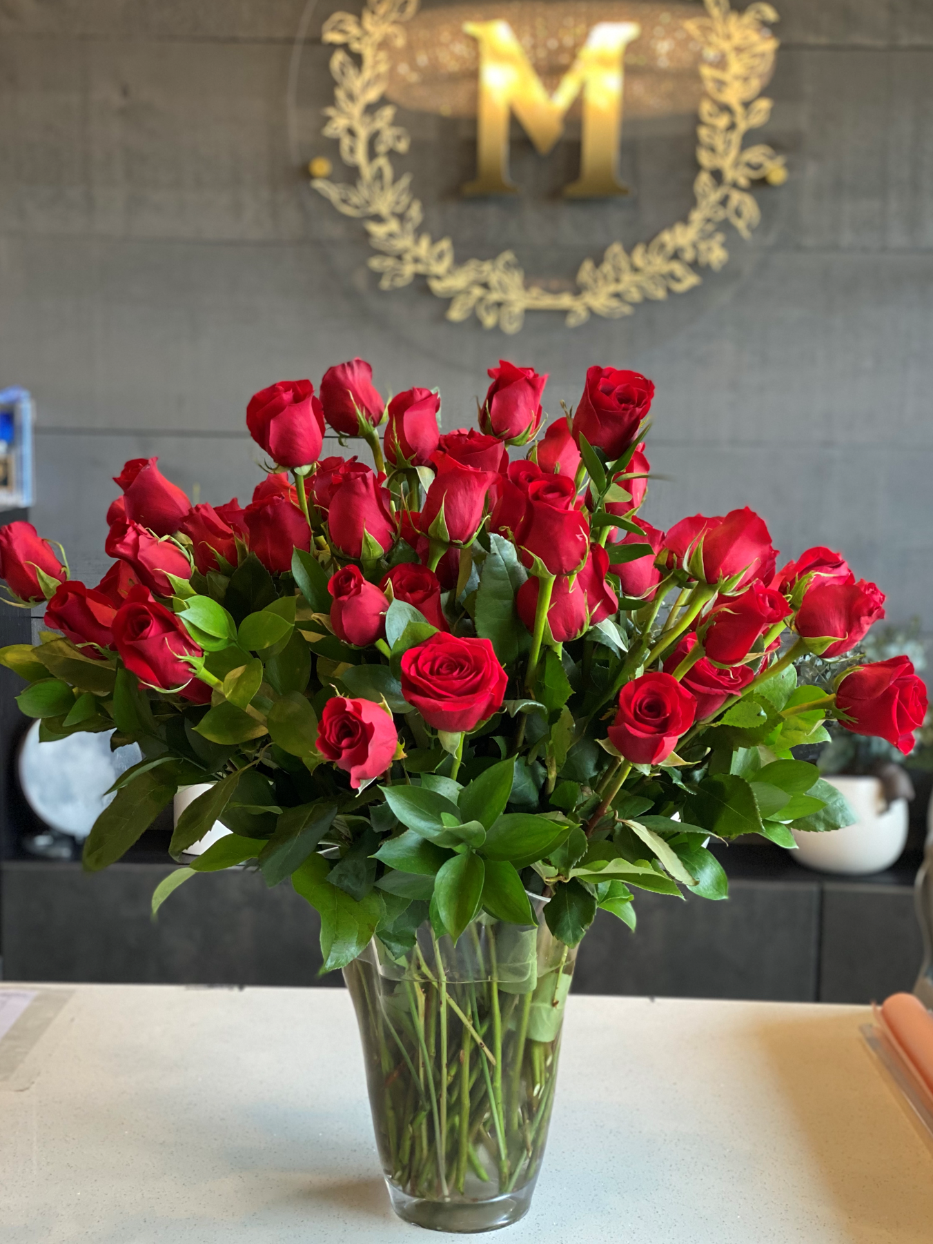 • A luxurious Mother's Day arrangement of premium red roses professionally arranged in a tall clear glass vase.
• Set against a modern background with Moon's Flowers signature gold logo, this elegant rose display is perfect for home delivery in Toronto.