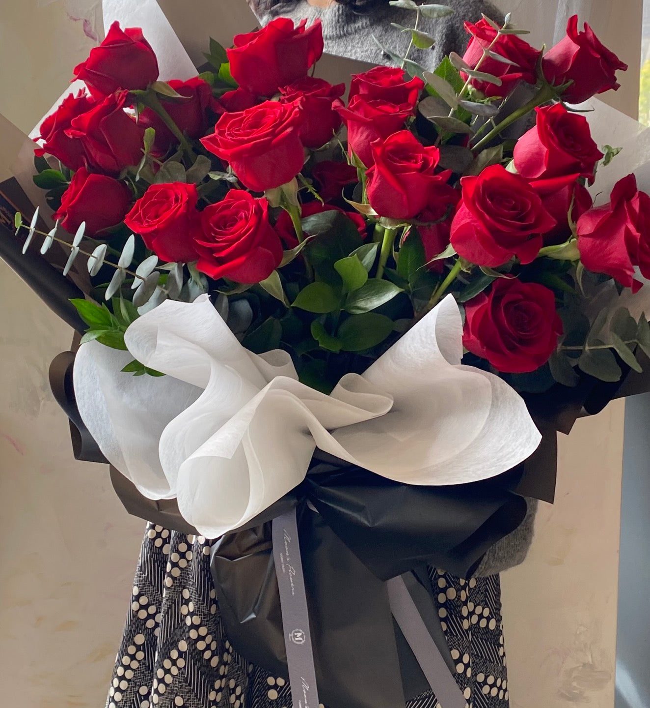 A stunning Mother's Day bouquet of premium red roses, elegantly hand-tied with black and white decorative wrapping and a grey signature ribbon. This classic romantic arrangement by Moon's Flowers Toronto is available for same-day delivery