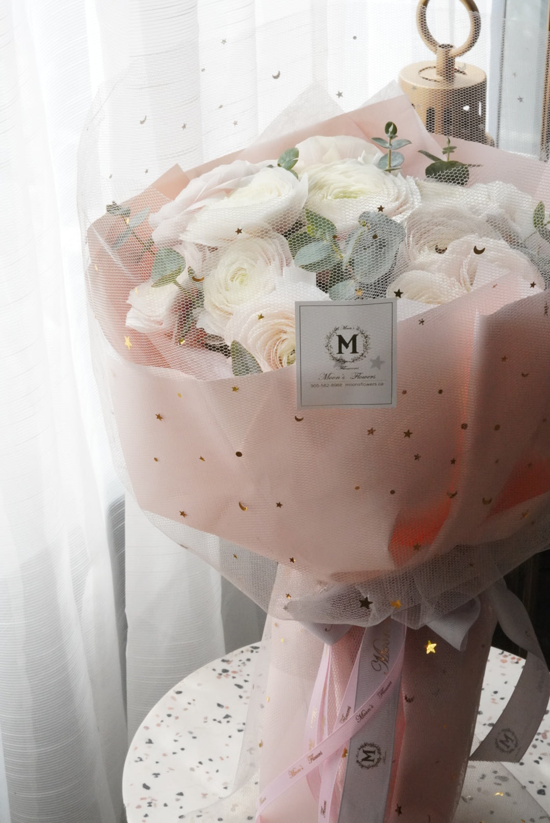 Blush and cream ranunculus bouquet with a whimsical star patterned wrap. Features large blush ranunculus and eucalyptus for chic, contemporary gift for Mother's Day/ flower delivery in Oakville, Toronto , and the GTA