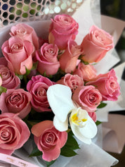 Blush pink rose bouquet with white orchid and fresh greenery in elegant wrapping