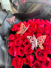 A bouquet of red roses with decorative butterfly add-ons.