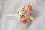 Close-up of blush pink boutonniere with spray roses, white stephanotis, and pearl pins on soft tulle — wedding boutonniere by Moon's Flowers Toronto