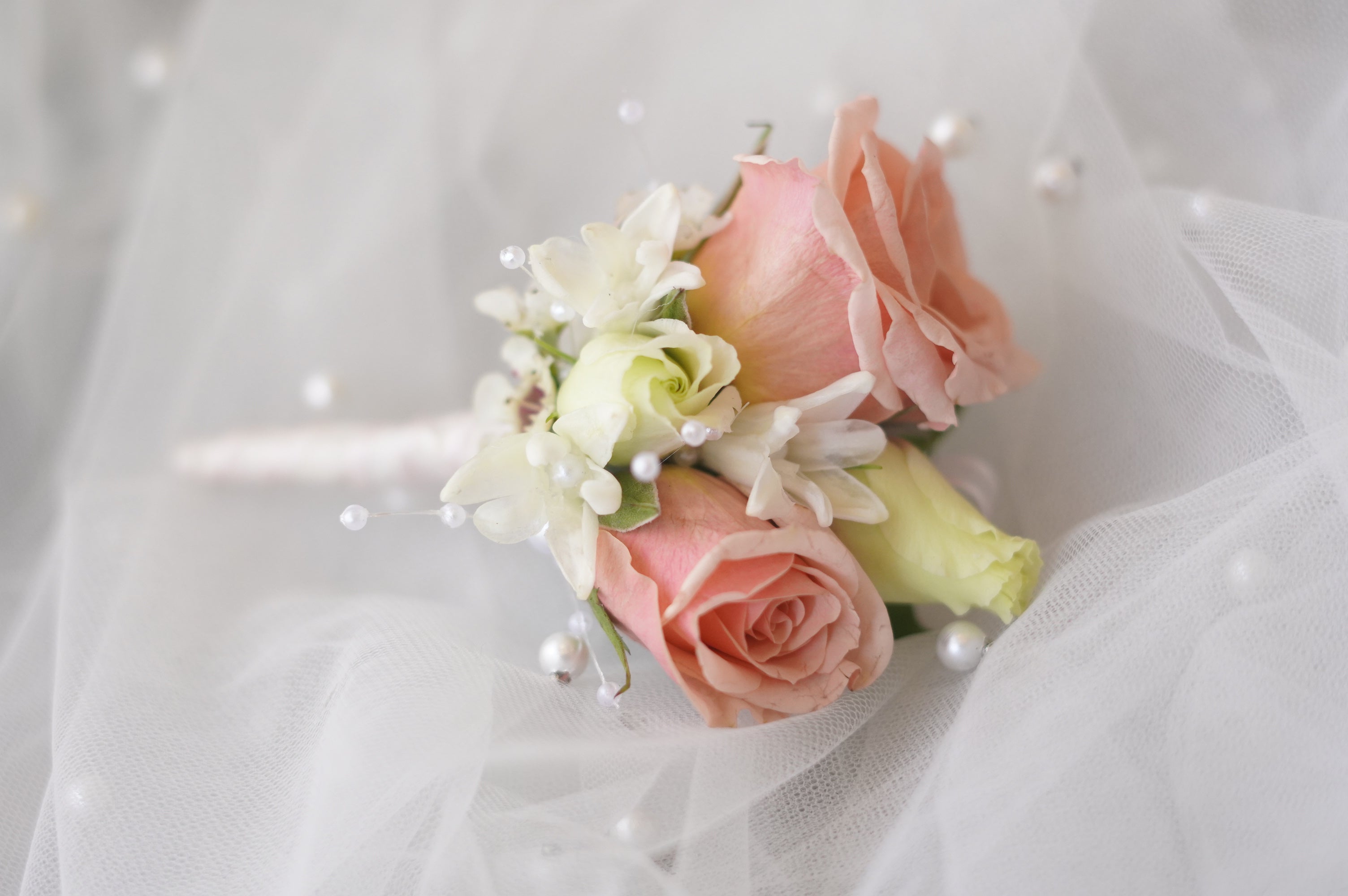 Close-up of blush pink boutonniere with spray roses, white stephanotis, and pearl pins on soft tulle — wedding boutonniere by Moon's Flowers Toronto