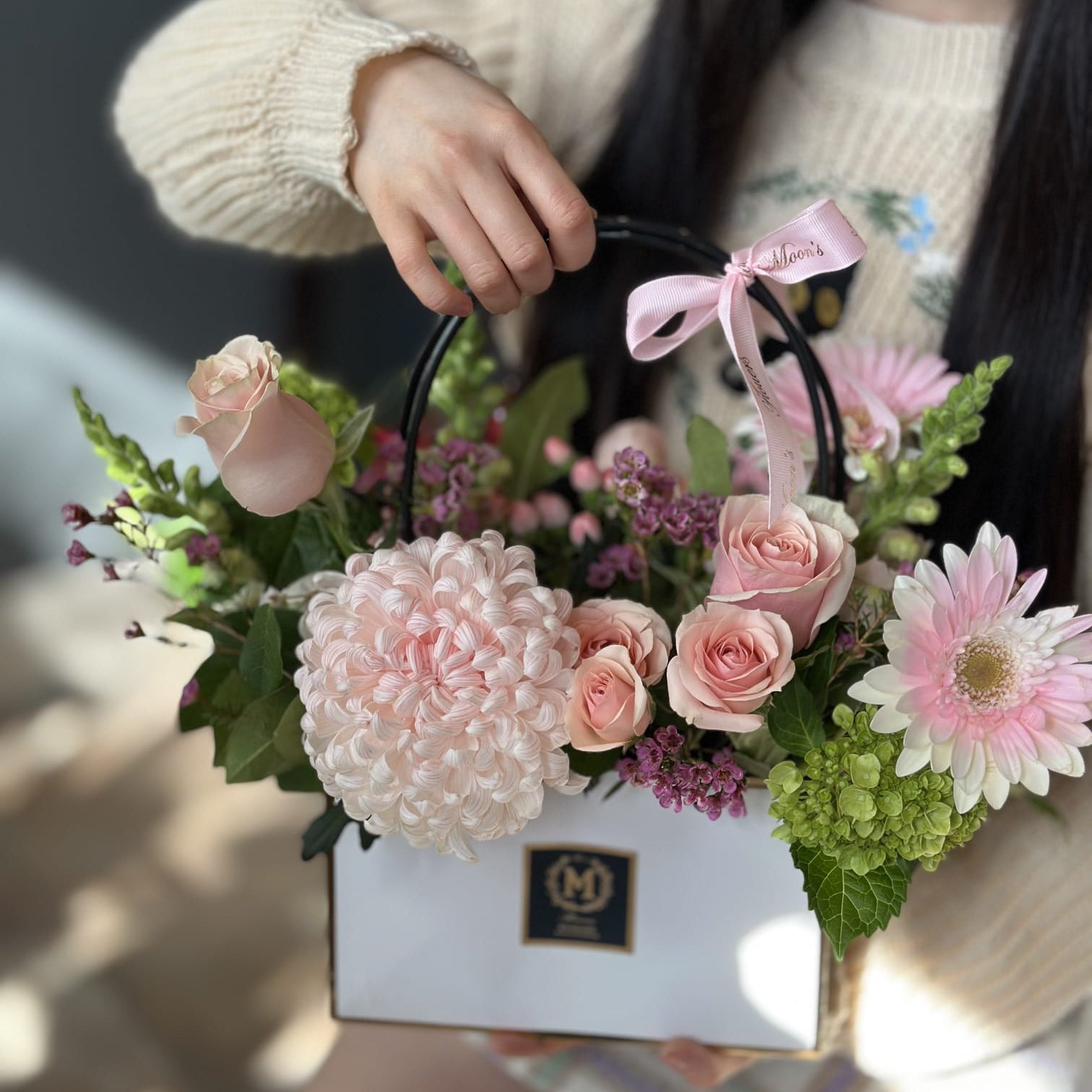 Chic floral gift bag from Moon's flowers featuring a large chrysanthemum, roses, and gerberas. a stylish and convenient ready to gift flower arrangement for delivery in Toronto and Oakville