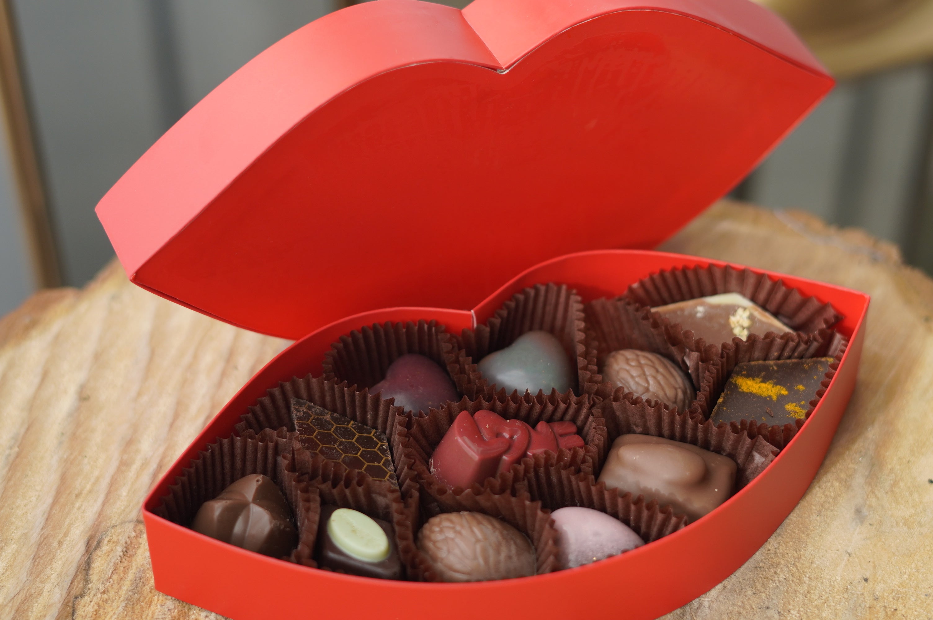 Red Lip-shaped box filled with chocolates on a wooden surface