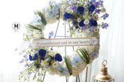 Circular funeral wreath with royal blue roses and white hydrangeas on a standing easel for Toronto delivery.