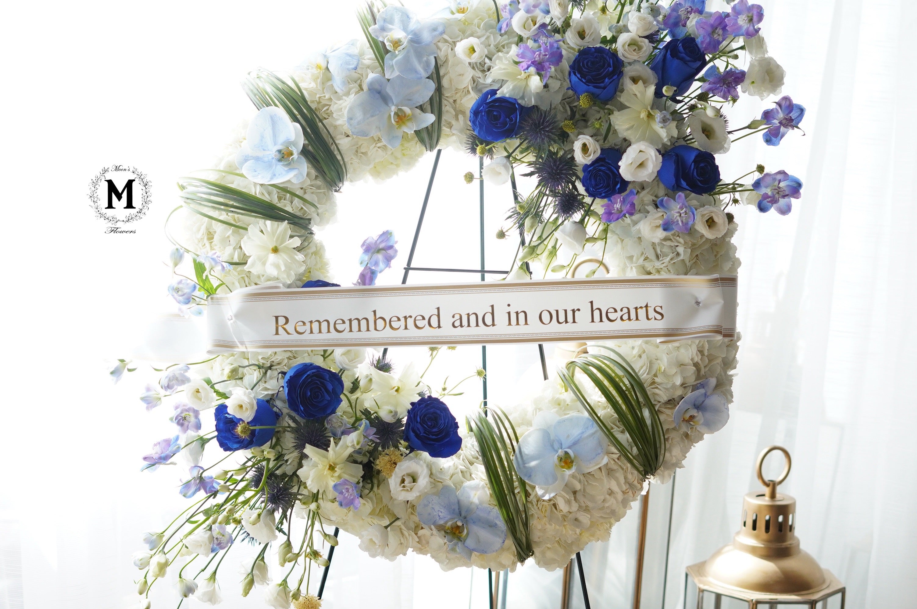Circular funeral wreath with royal blue roses and white hydrangeas on a standing easel for Toronto delivery.