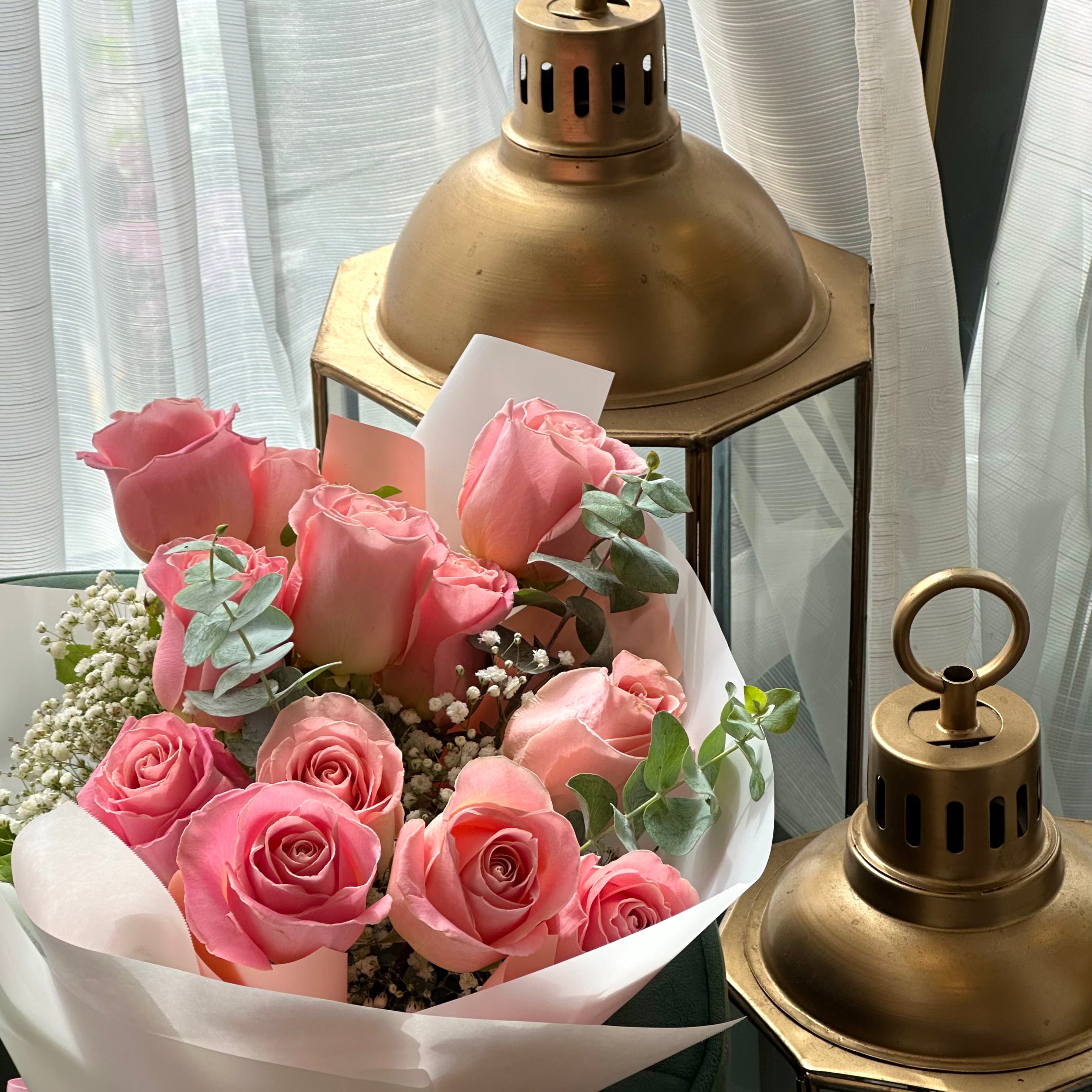Classic pink rose dozen bouquet styled on a chair with roses and greenery
