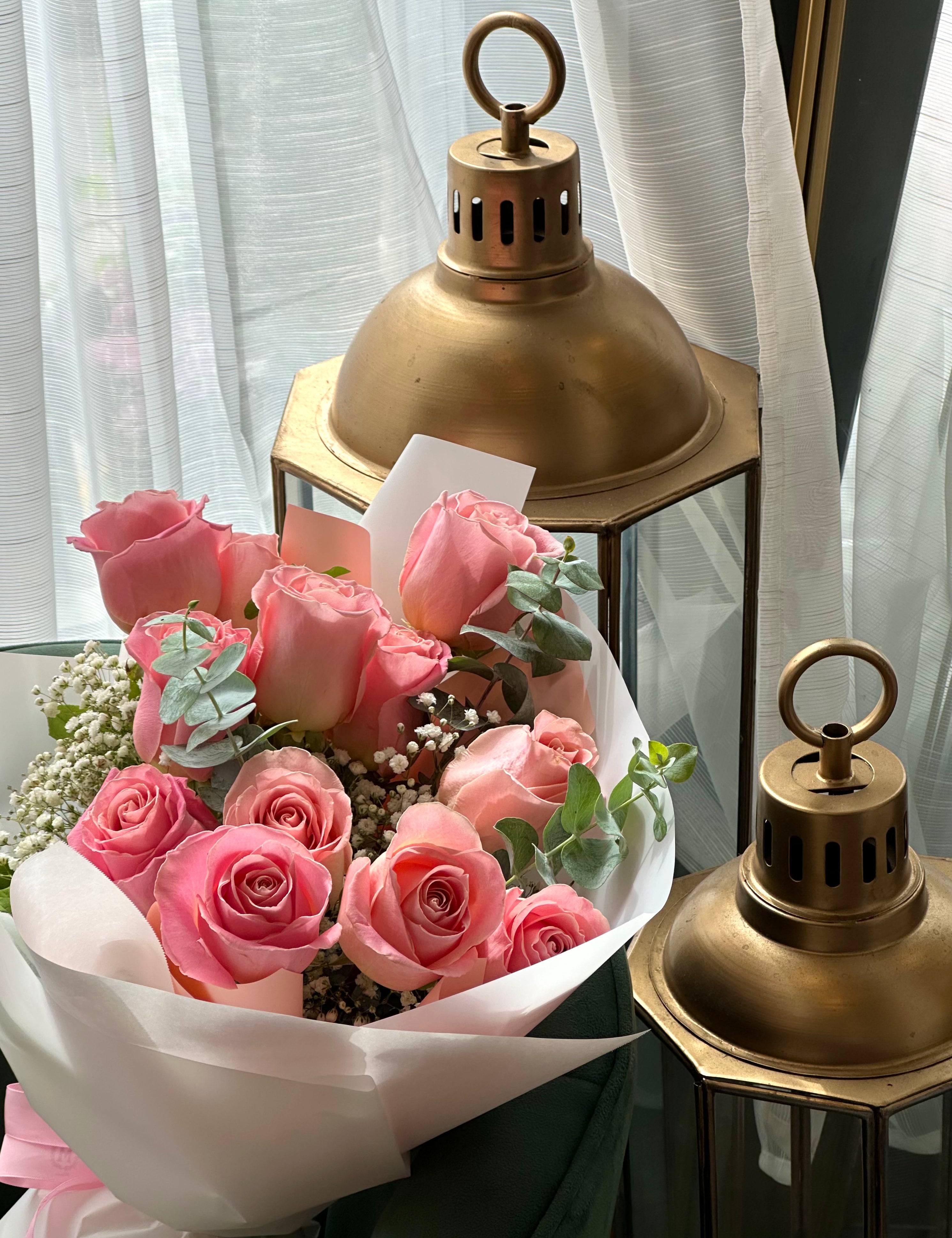 Classic pink rose dozen bouquet styled on a chair with roses and greenery