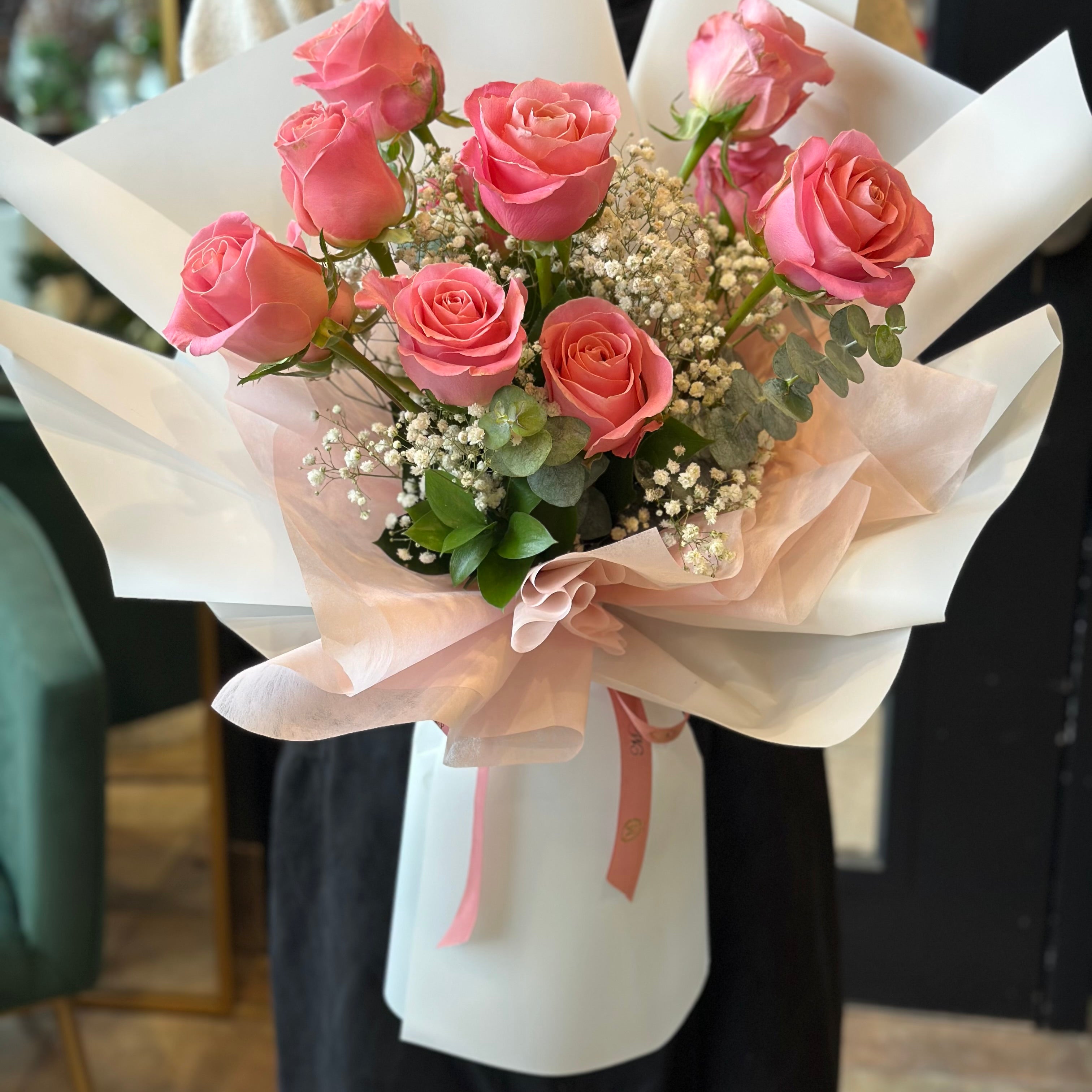 Handheld classic pink rose bouquet arranged with greenery in a natural style