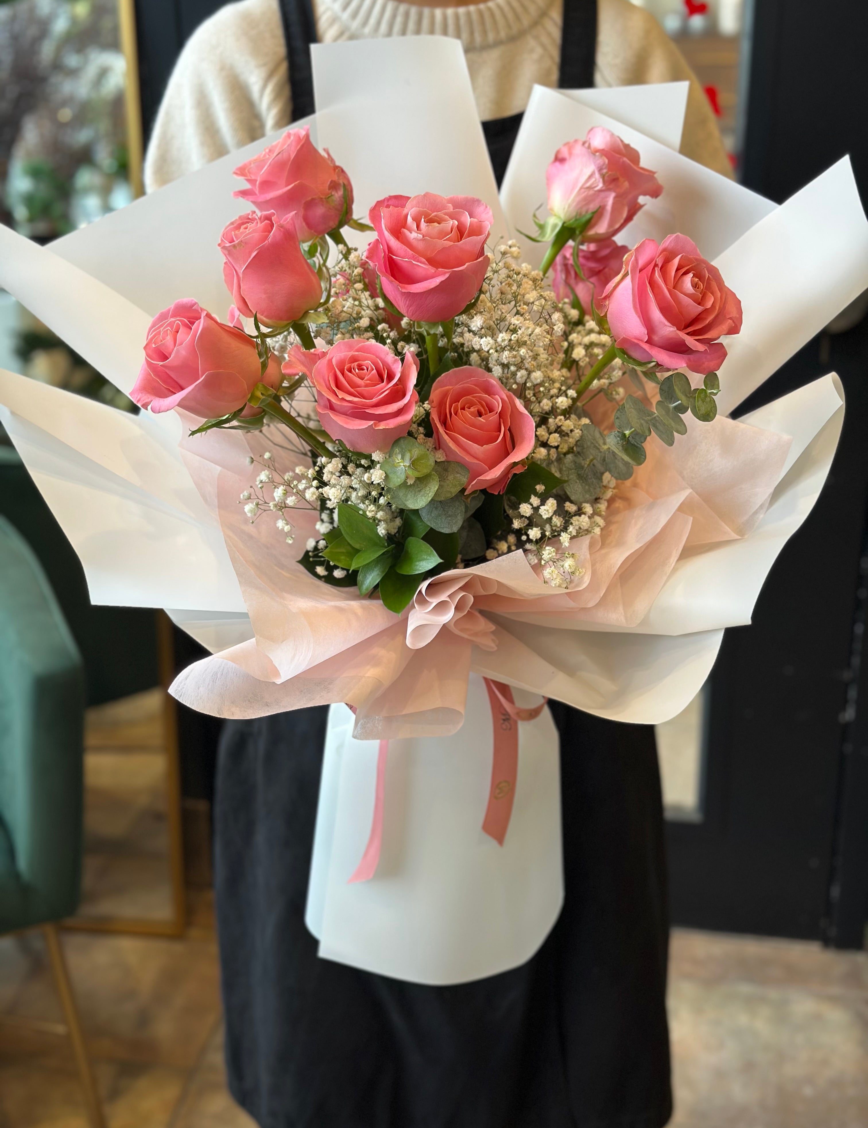 Handheld classic pink rose bouquet arranged with greenery in a natural style