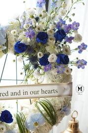 Close-up of premium blue roses and lavender blooms in a condolence wreath arrangement.