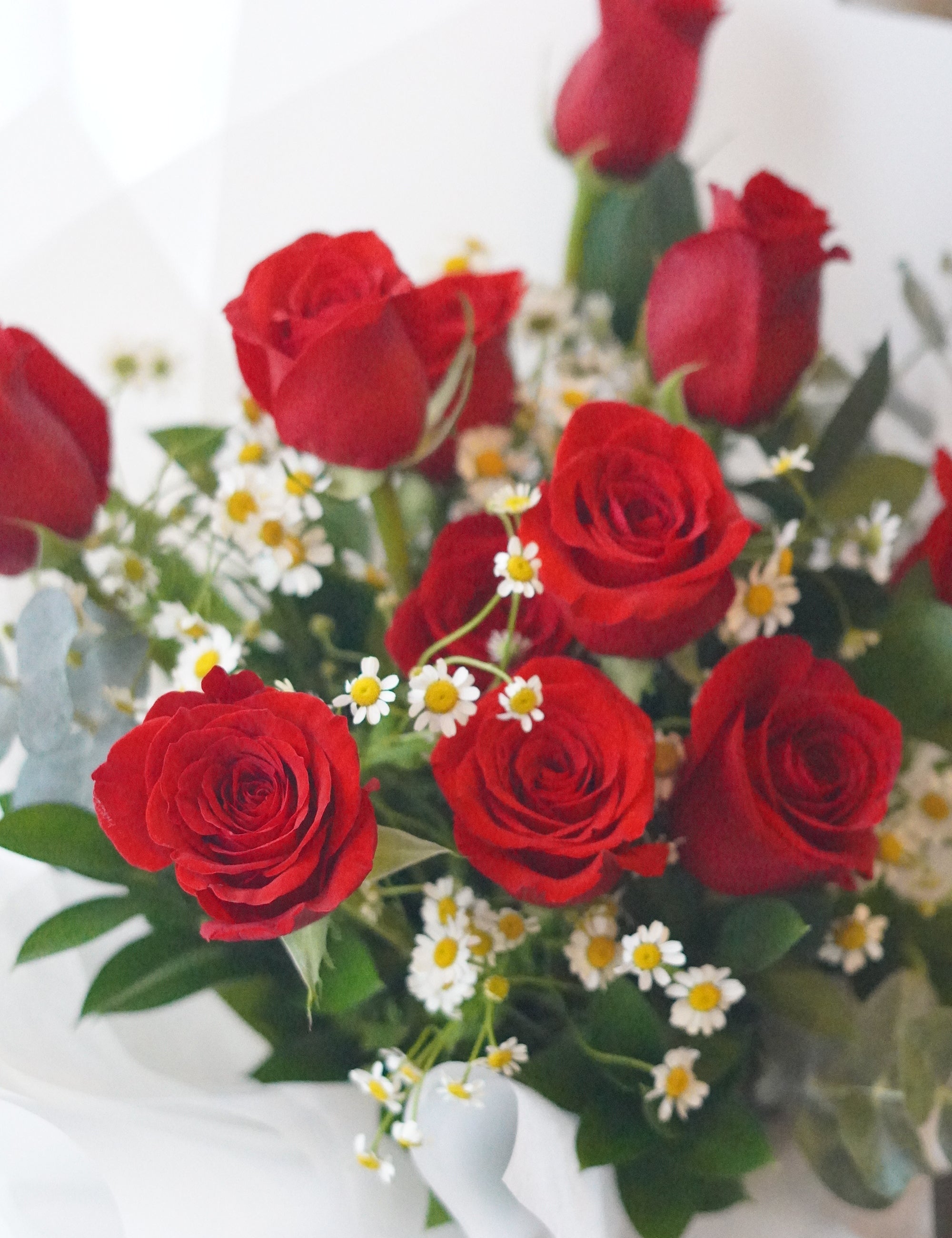 Close-up of red roses with chamomile flowers highlighting a natural garden-style arrangement