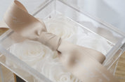 Close up of White preserved roses in an acrylic box, showcasing the intricacy of the flowers and the contrasting ribbon colours.