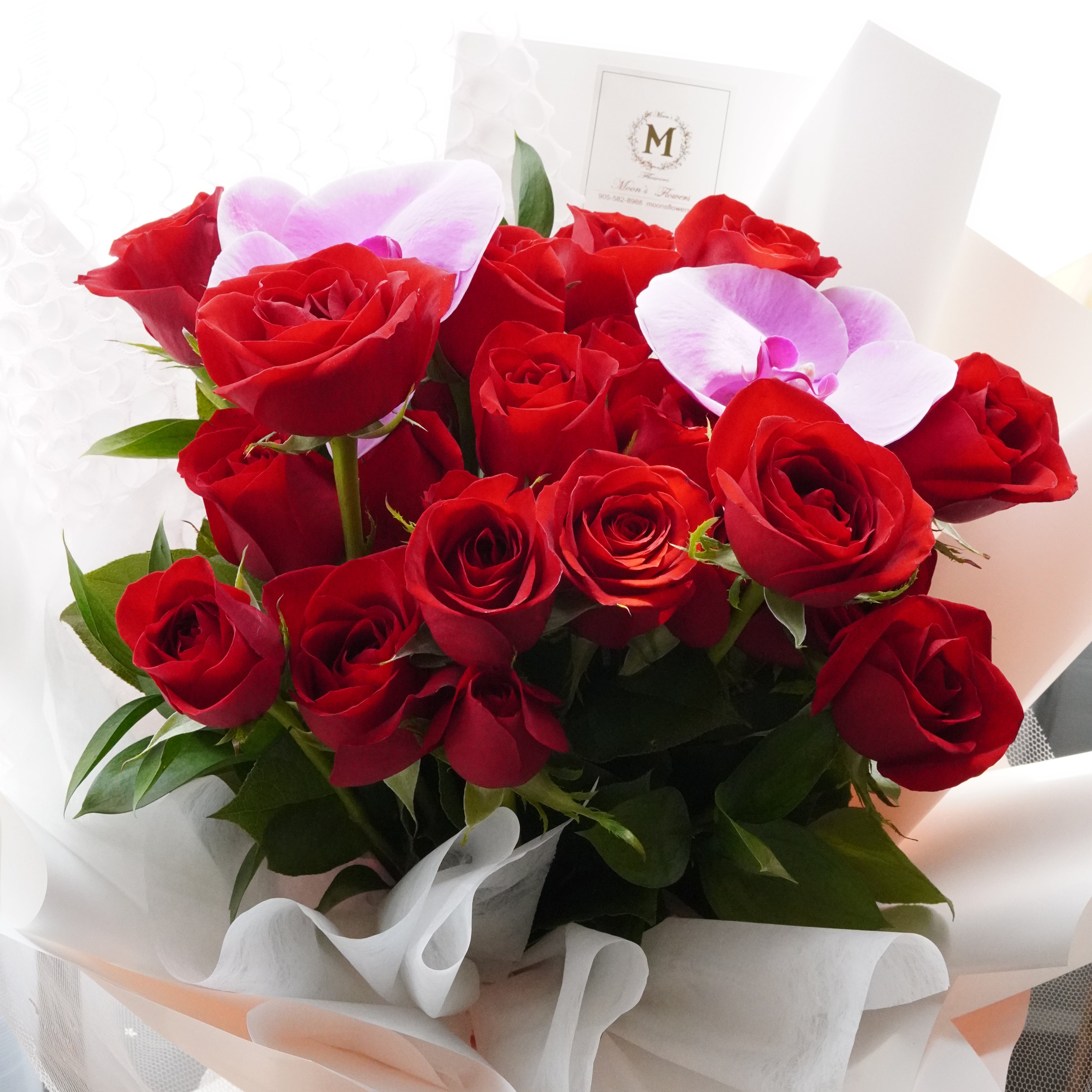 red two dozen rose bouquet with a white orchid accent
