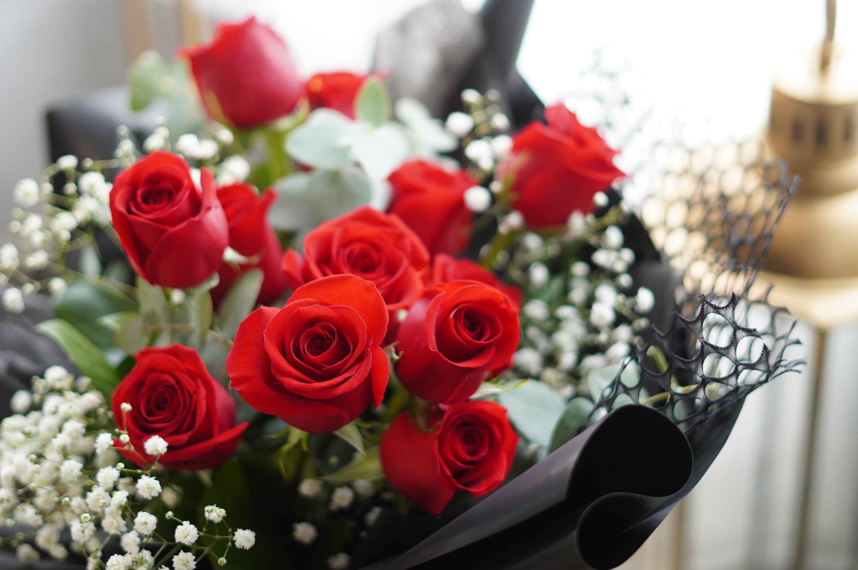 Classic red rose dozen bouquet styled on a chair with roses and greenery