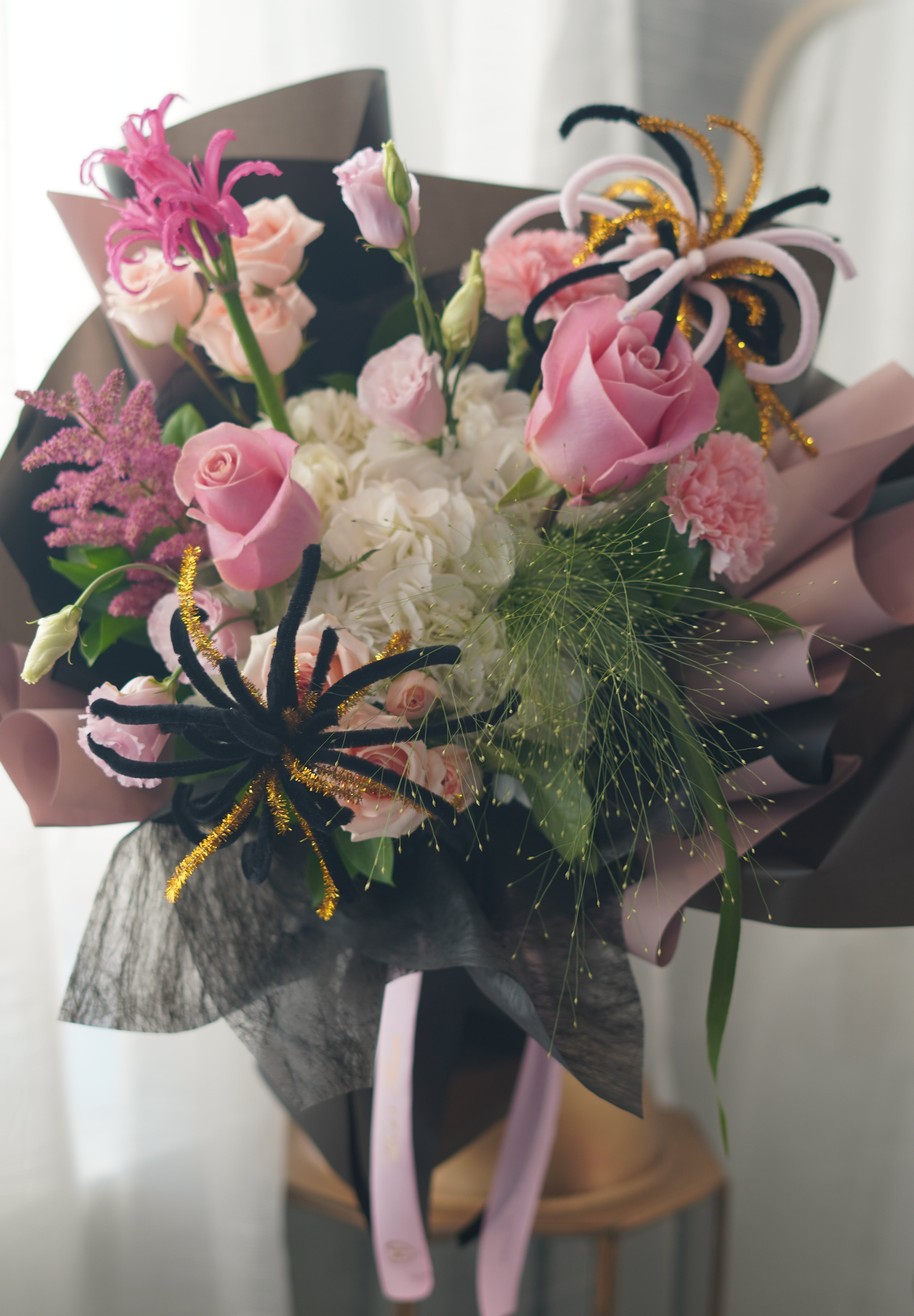 Pink roses and white hydrangea with black, pink and gold firework-inspired accents — graduation bouquet