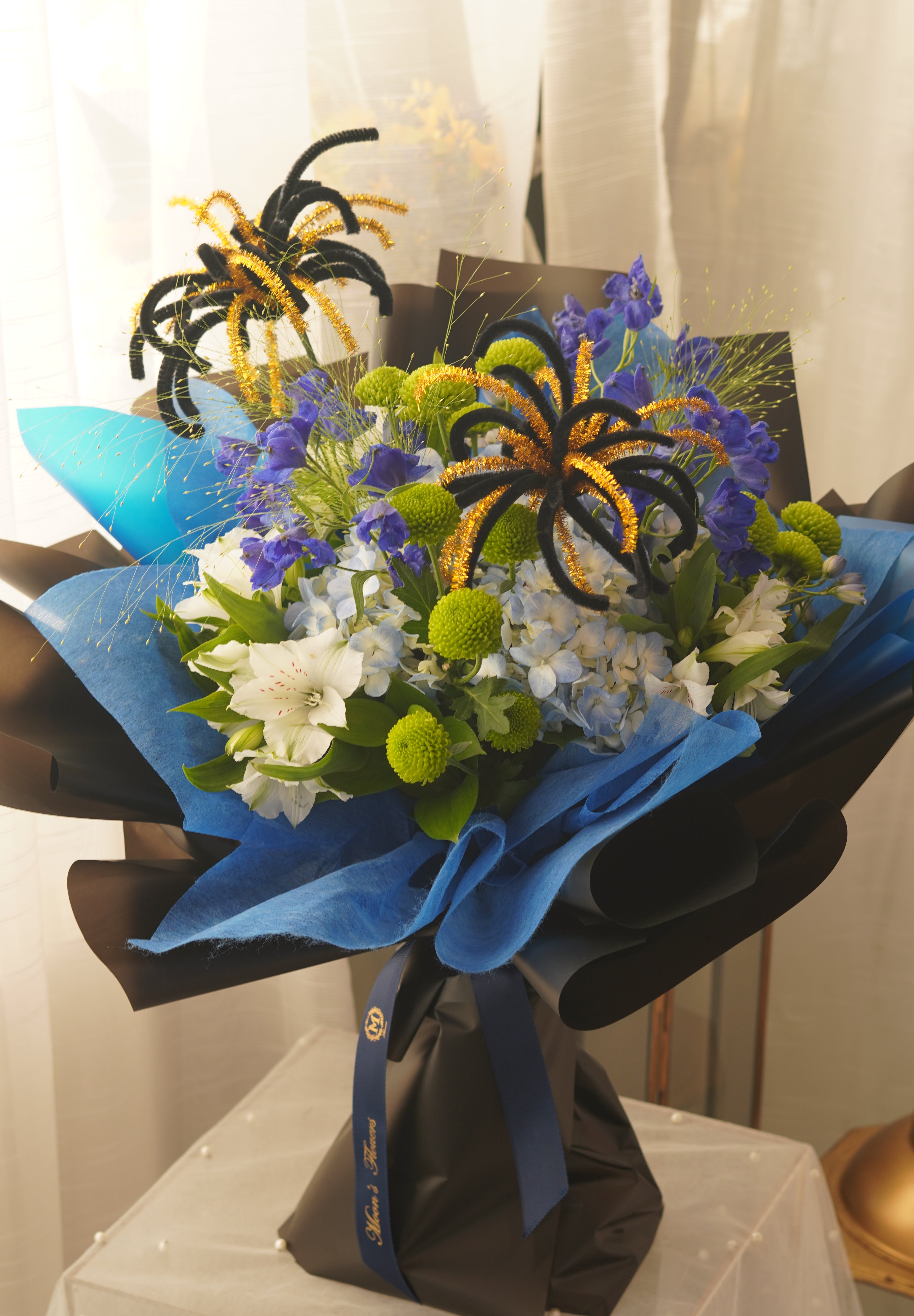 Blue Horizon graduation bouquet with blue and white flowers, green chrysanthemums and blue-black wrapping for Toronto graduates