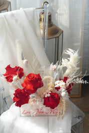 Preserved red rose arrangement with dried white florals in a transparent box featuring "Love You Mom" calligraphy.