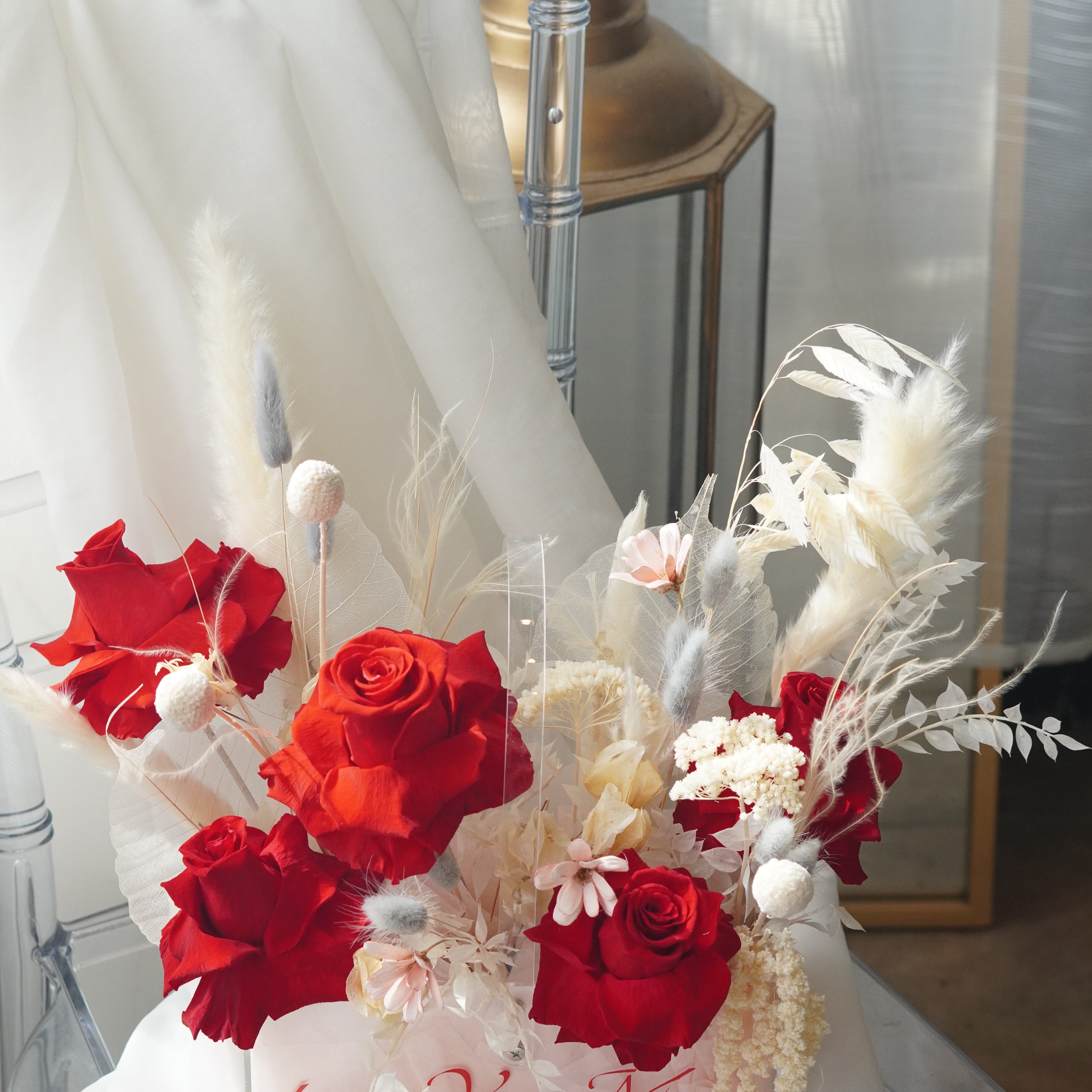 Preserved red rose arrangement with dried white florals in a transparent box featuring "Love You Mom" calligraphy.