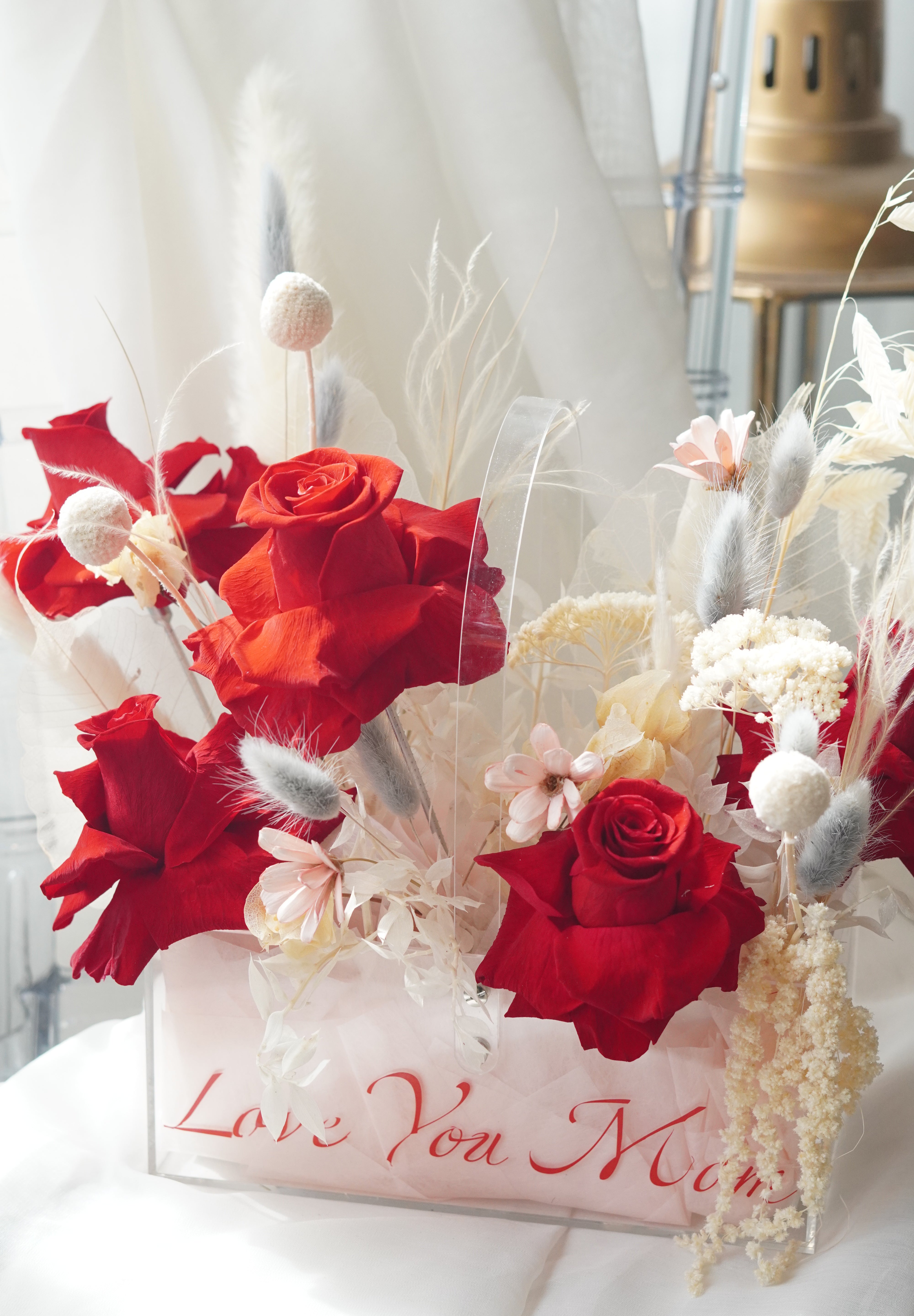 Luxury floral arrangement titled Velvet Love Bloom, featuring deep red preserved roses, white pampas grass, and neutral dried textures in a modern acrylic box.