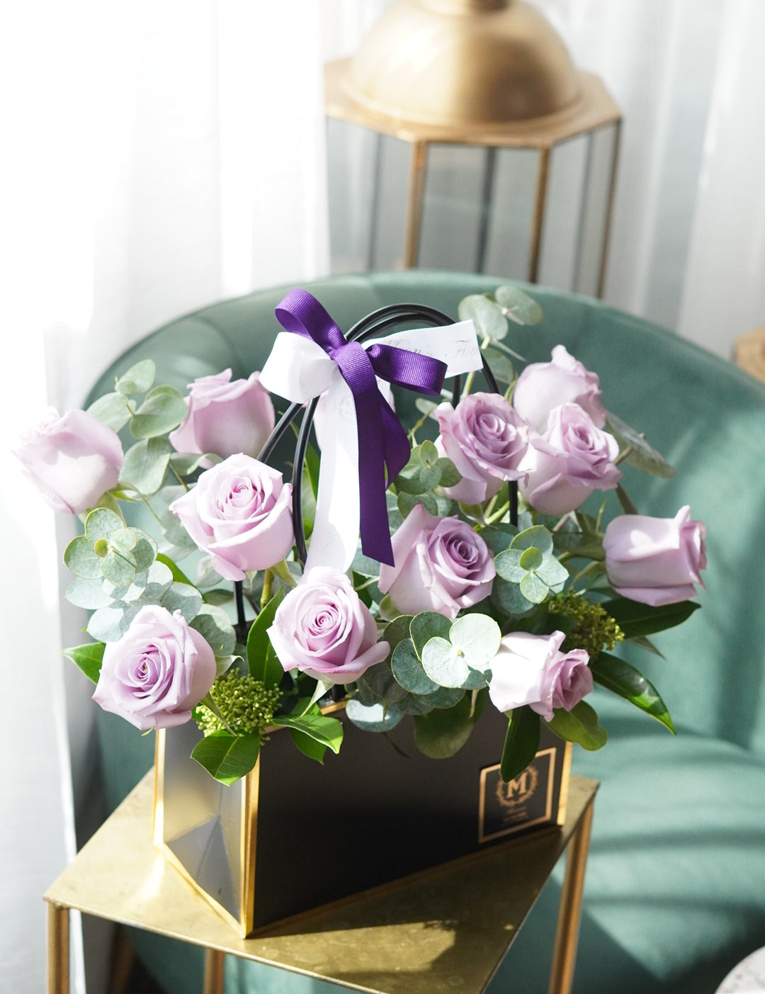 Dozen lavender roses arranged in a modern basket with purple and light purple roses