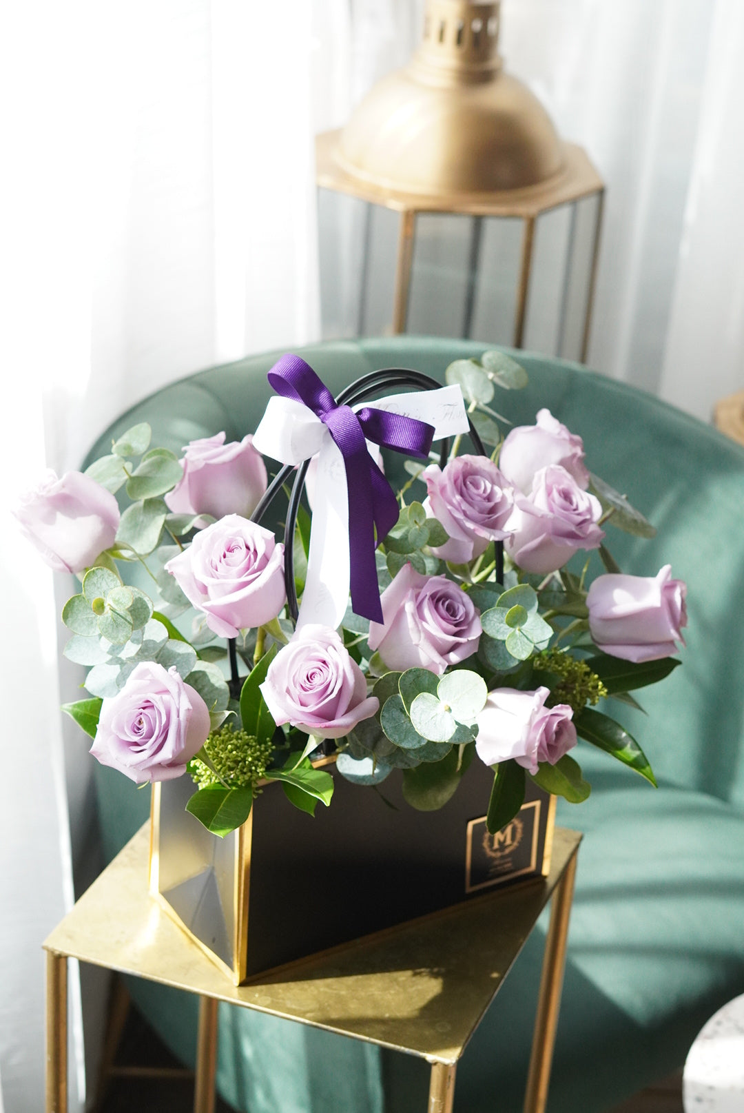 Dozen lavender roses arranged in a modern basket with purple and light purple roses