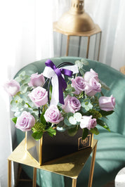 Dozen lavender roses arranged in a modern basket with purple and light purple roses