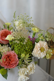 Close-up of premium coral garden roses, green hydrangeas, Queen Anne's Lace, and seasonal flowers in the Sunday Brunch centerpiece.