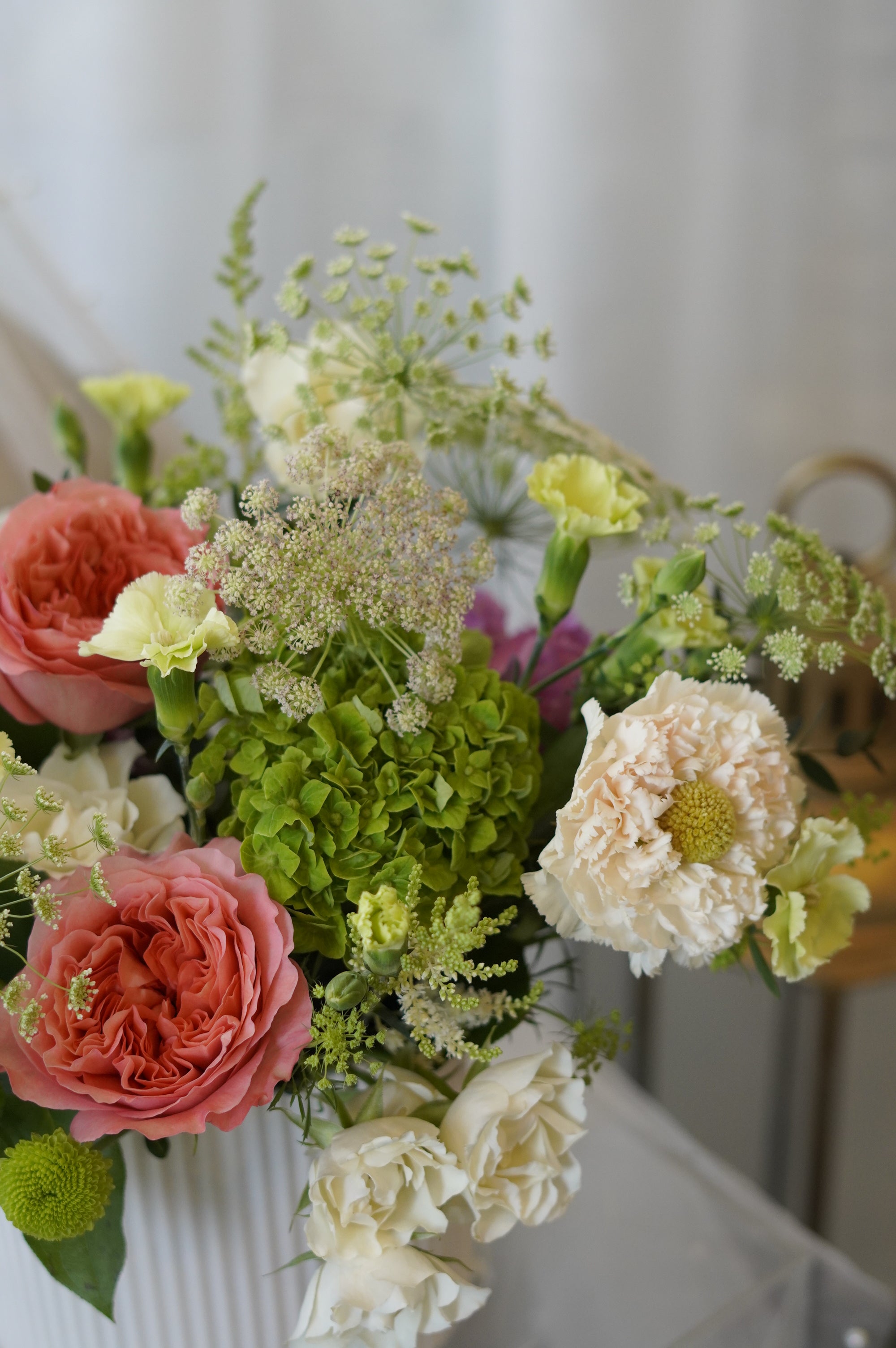 Close-up of premium coral garden roses, green hydrangeas, Queen Anne's Lace, and seasonal flowers in the Sunday Brunch centerpiece.