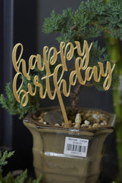  Gold "happy birthday" acrylic cake topper inserted into a bonsai plant