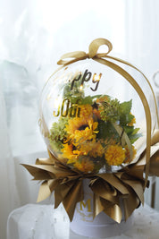Artificial flower balloon arrangement with soft blush pink and peach flowers inside a clear display dome with tulle and ribbon