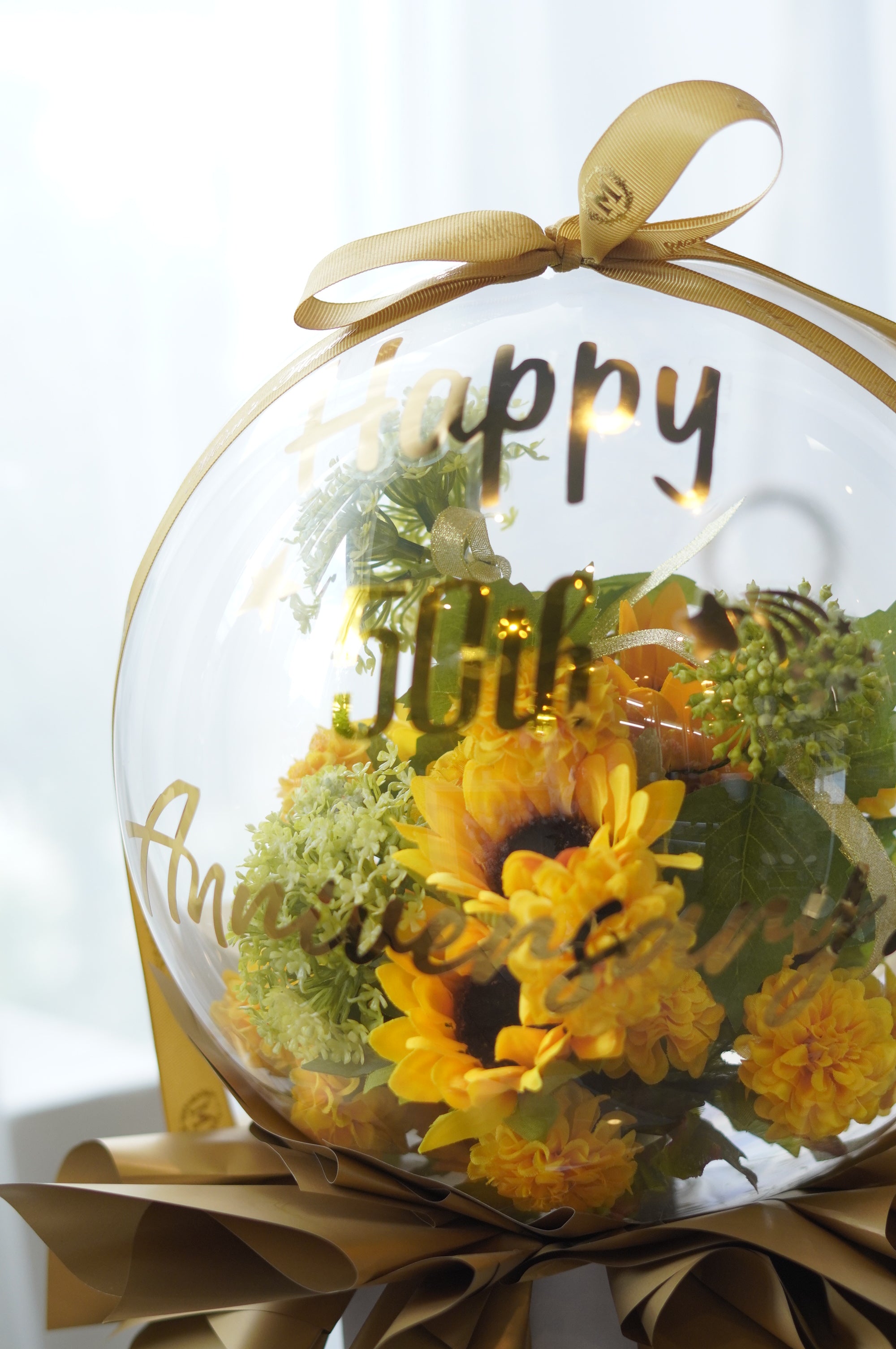 Sunflower flower balloon arrangement with gold lettering reading "Happy 50th Anniversary" topped with a gold ribbon