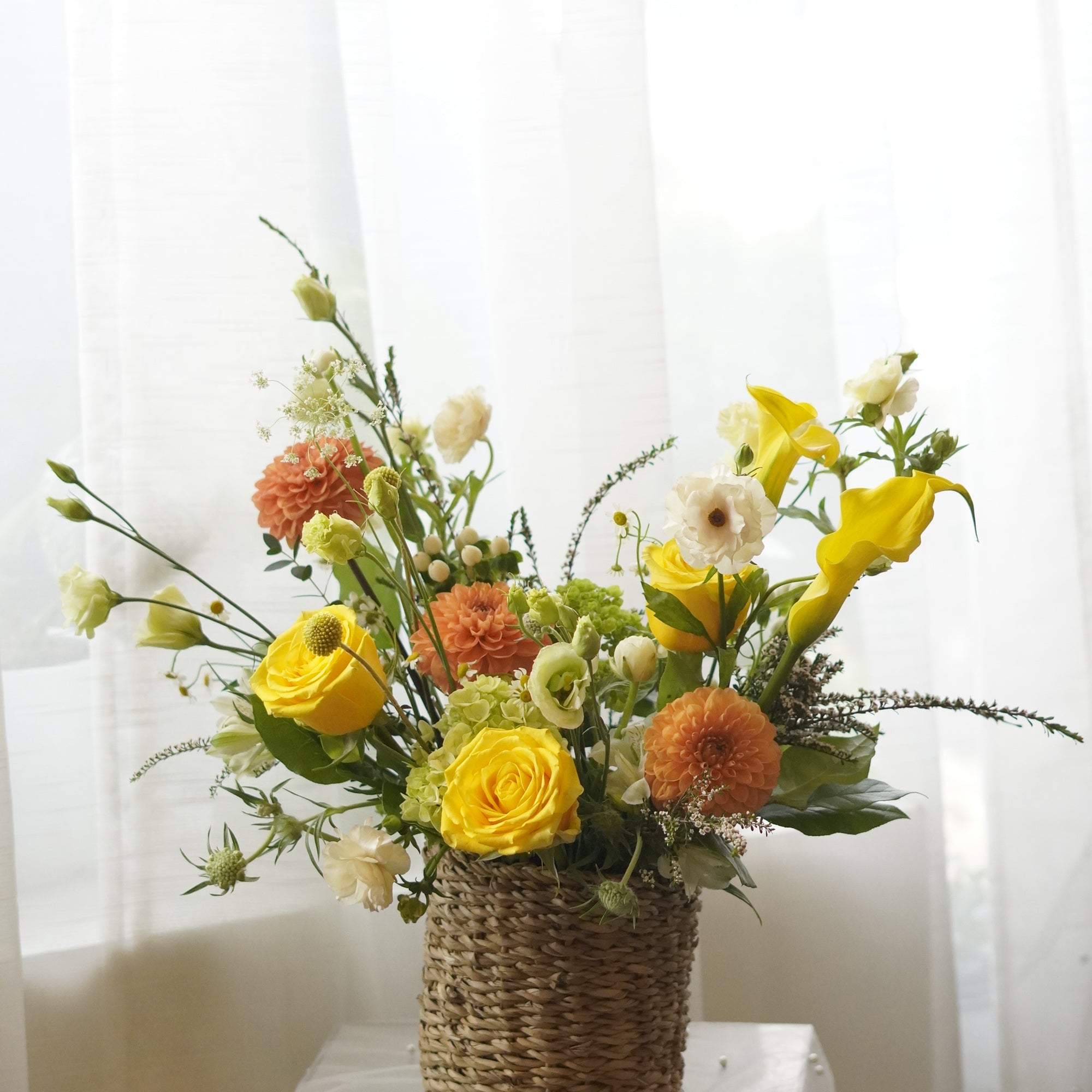 Yellow and orange seasonal flower basket with roses and garden flowers
