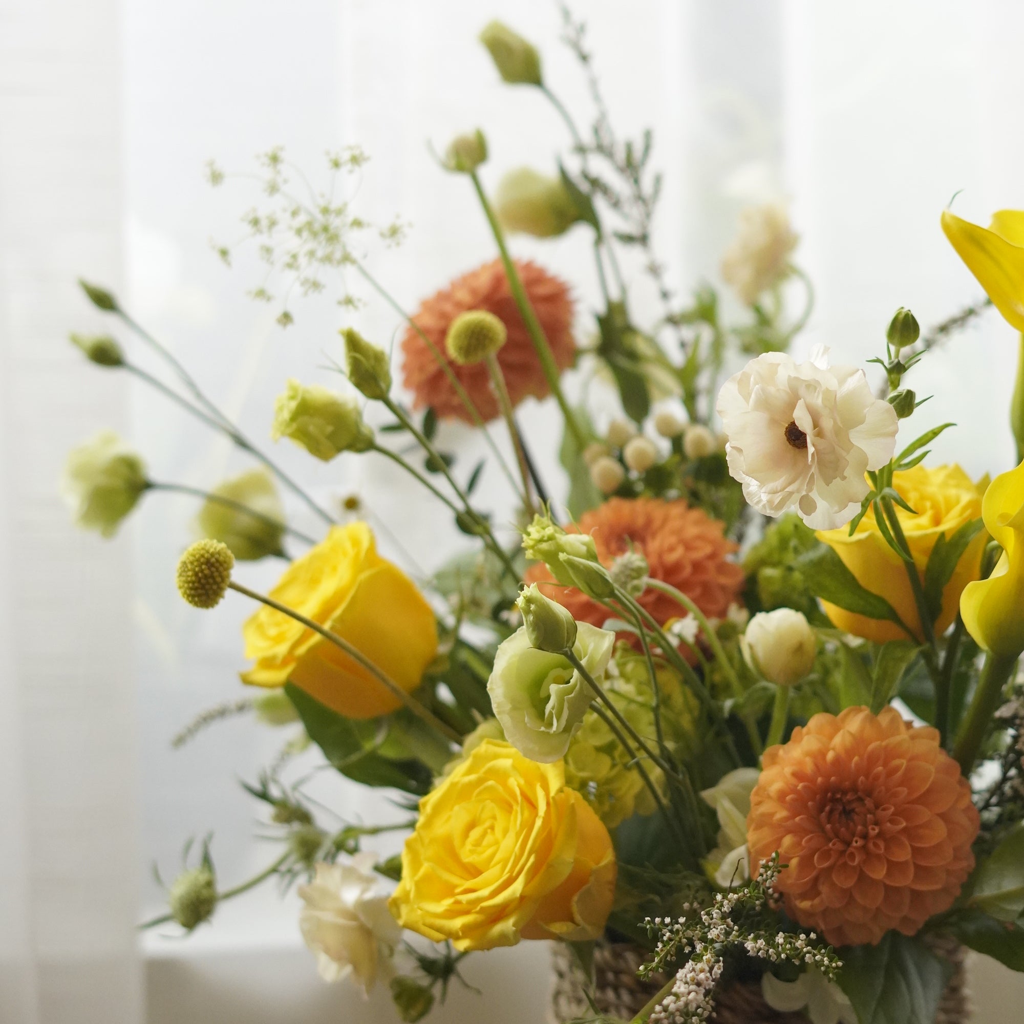 Yellow and orange seasonal flower basket with roses and garden flowers