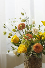 Yellow and orange seasonal flower basket with roses and garden flowers