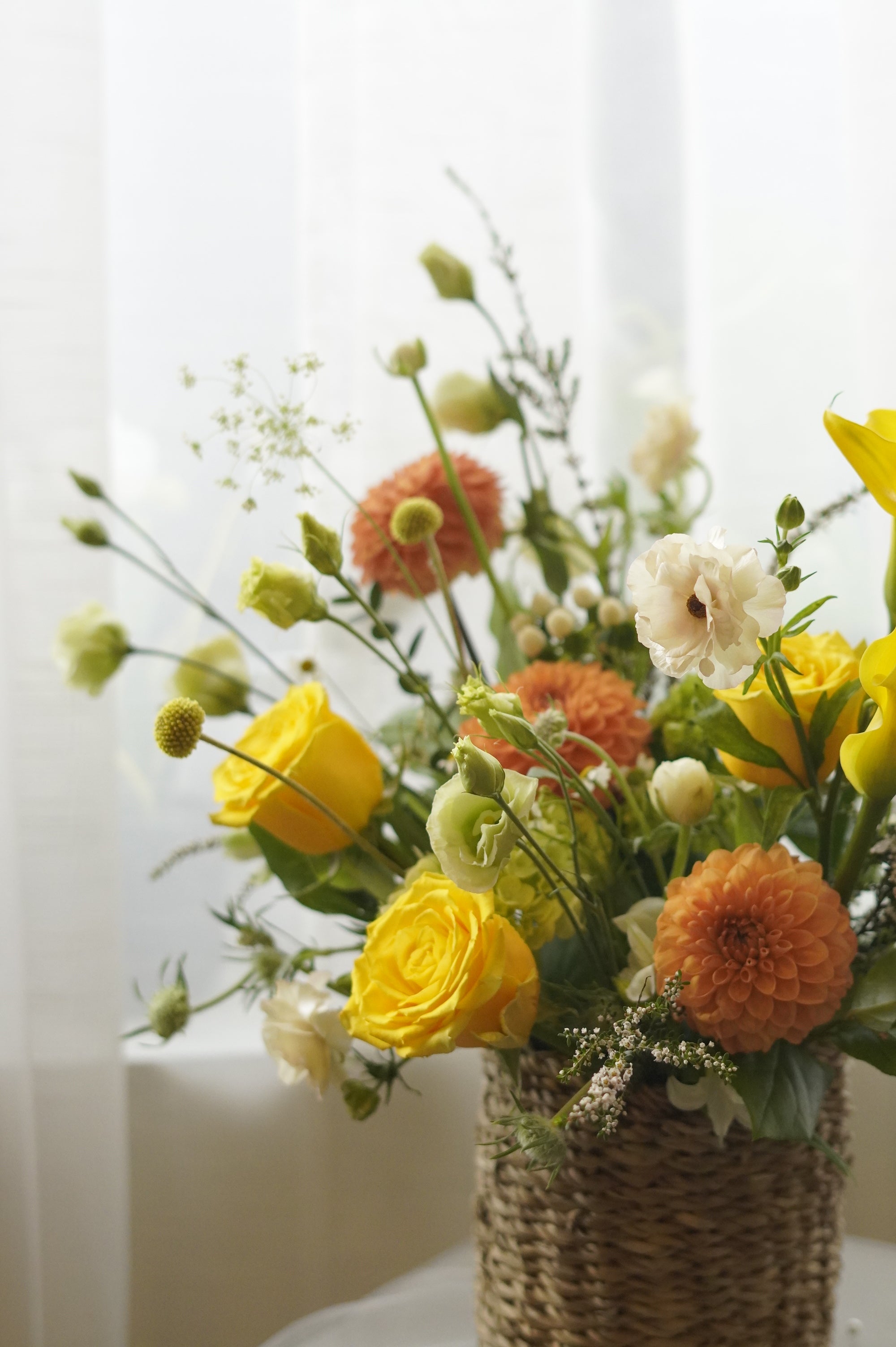Yellow and orange seasonal flower basket with roses and garden flowers
